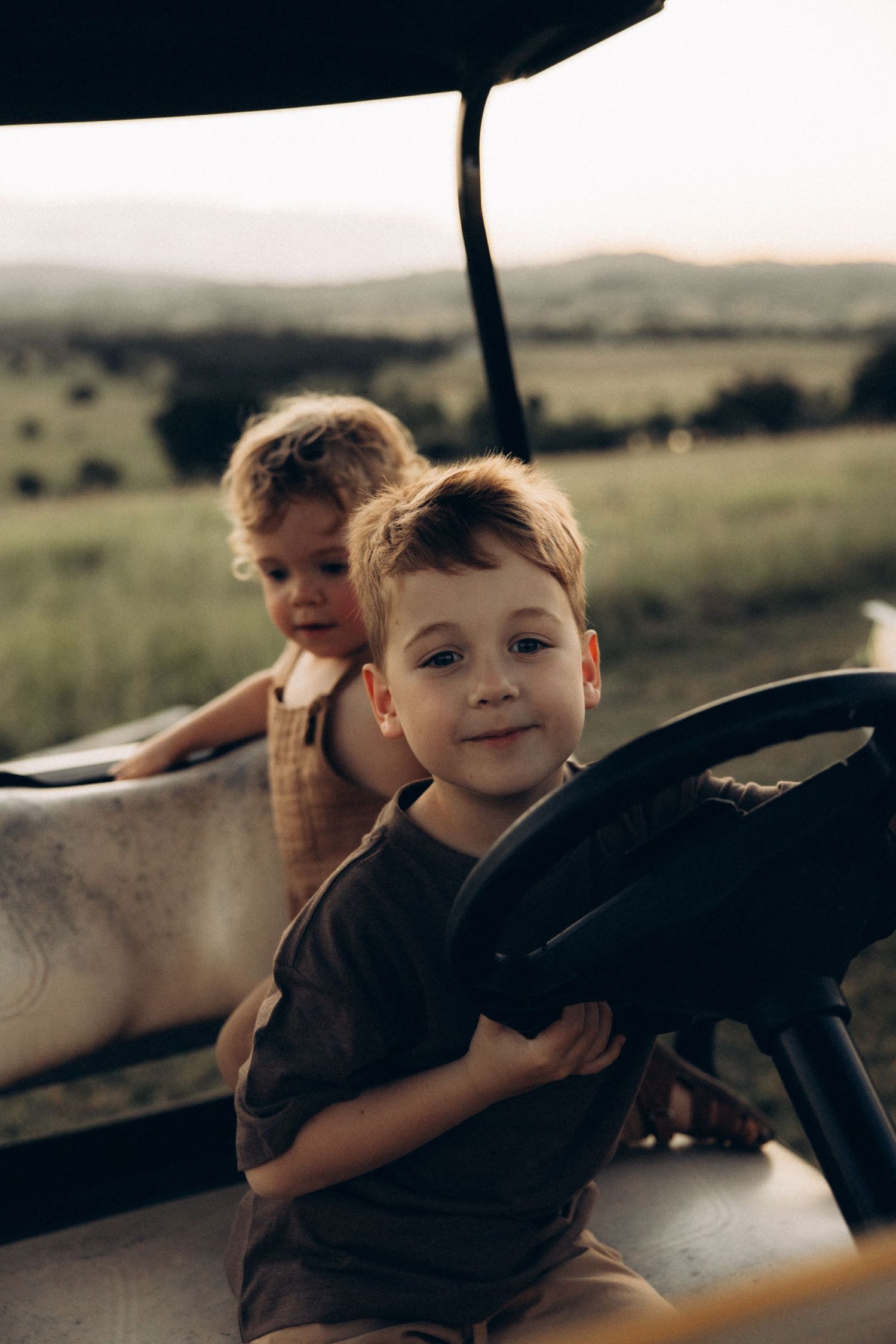 Children play together in a car during a countryside adventure.