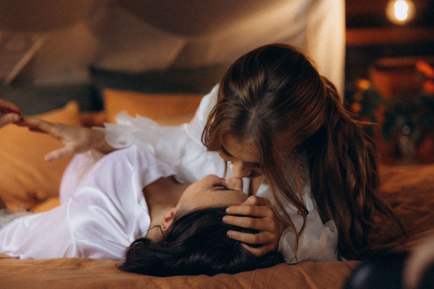 Intimate couple sharing tender moments while lying down together in warm lighting.