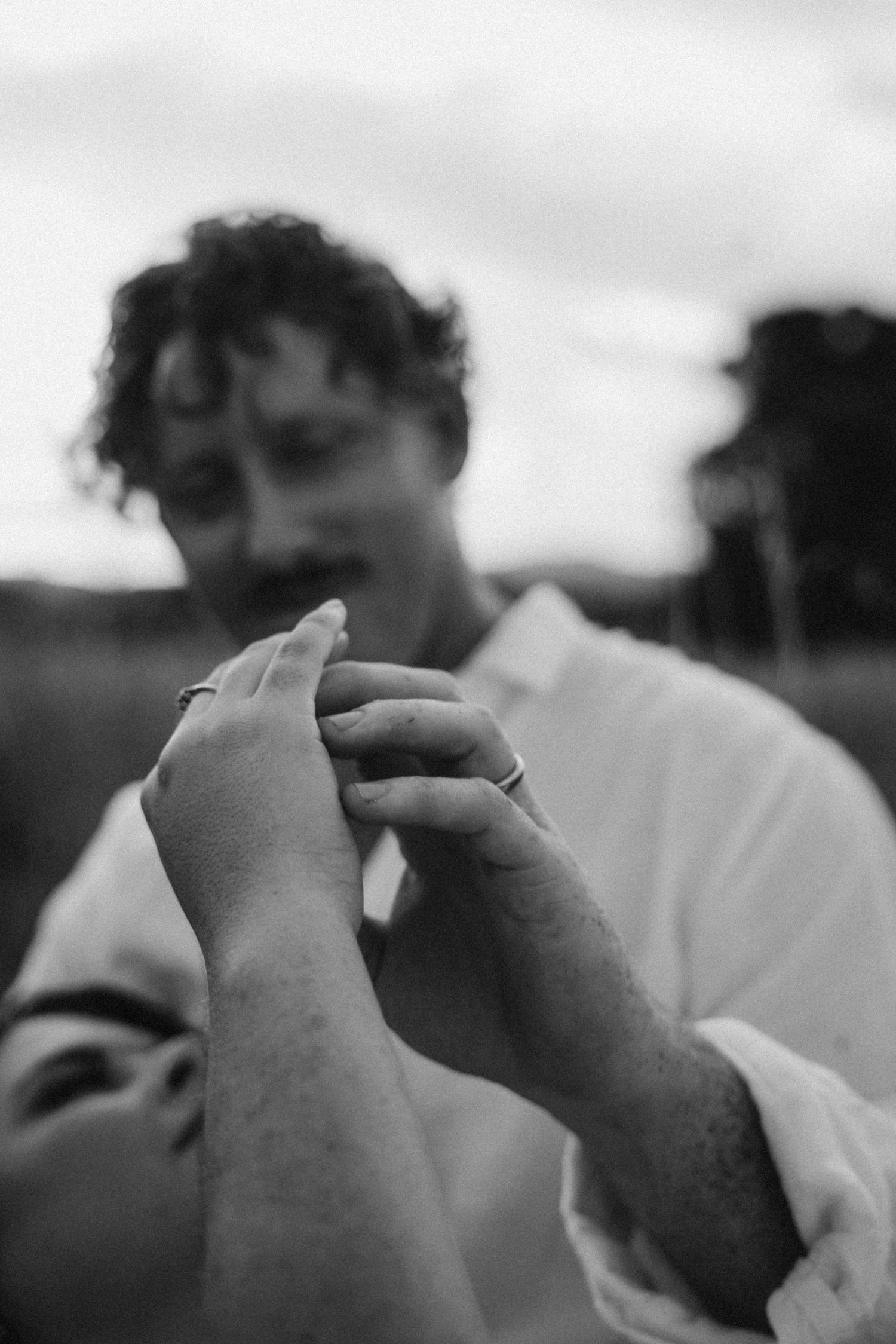 Close-up black and white photo of hands tenderly touching in an intimate moment.