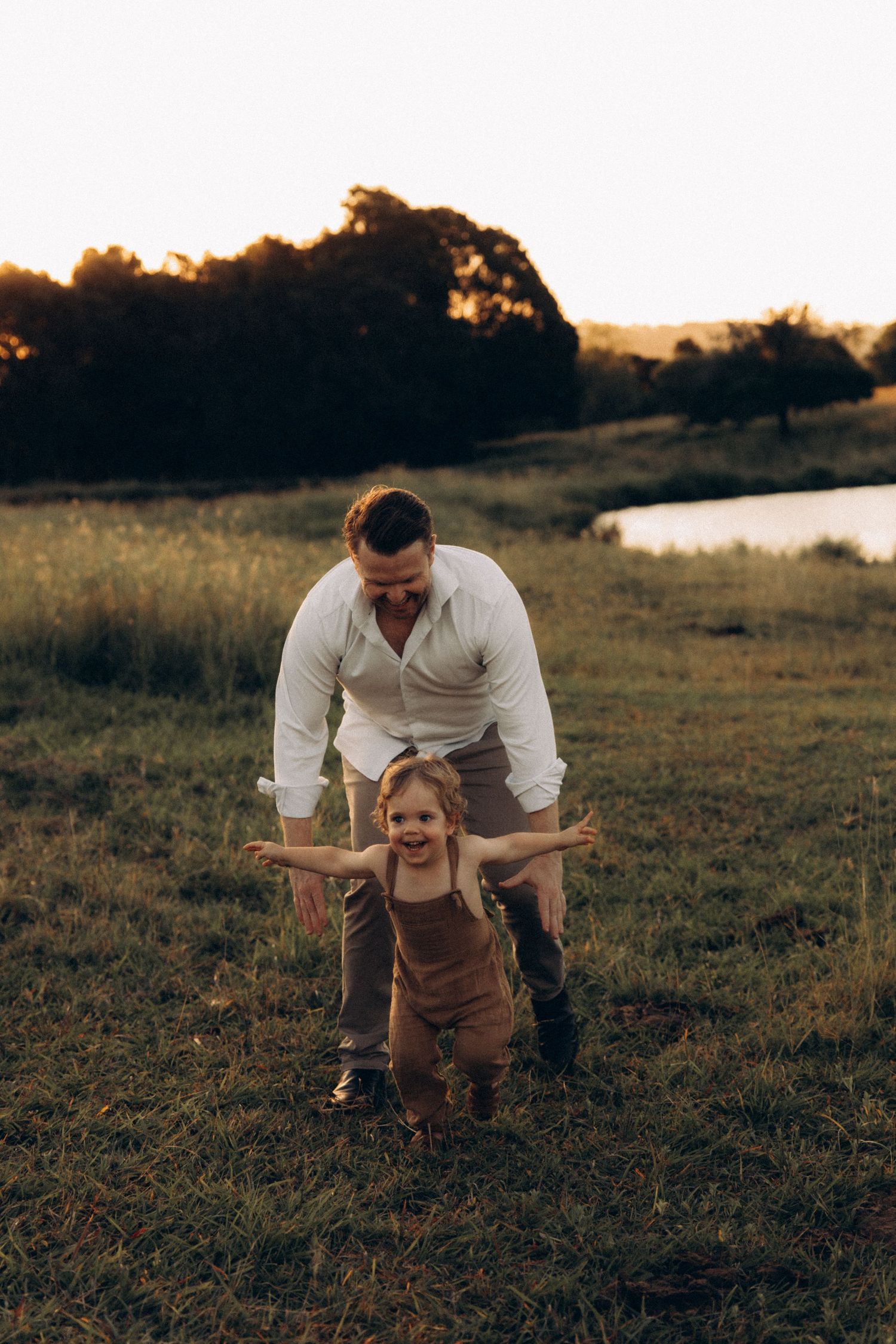 Playful family interaction captured in a field at sunset.
