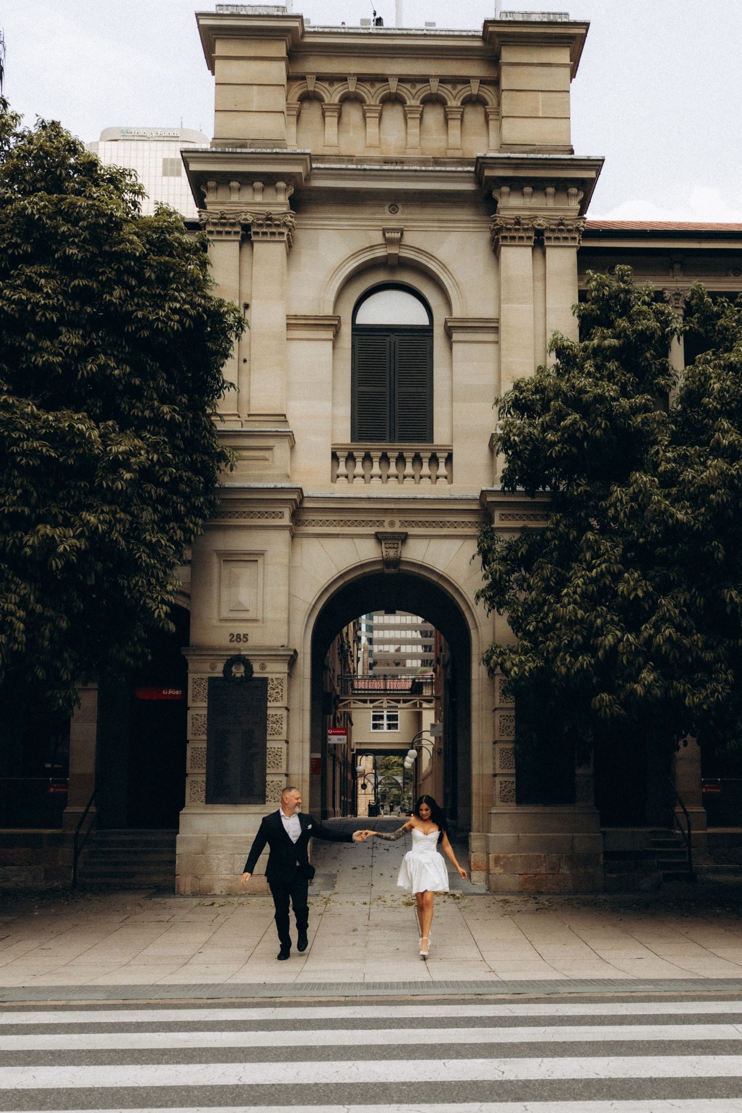 Elegant architectural entrance with couple walking through classical stone archway.