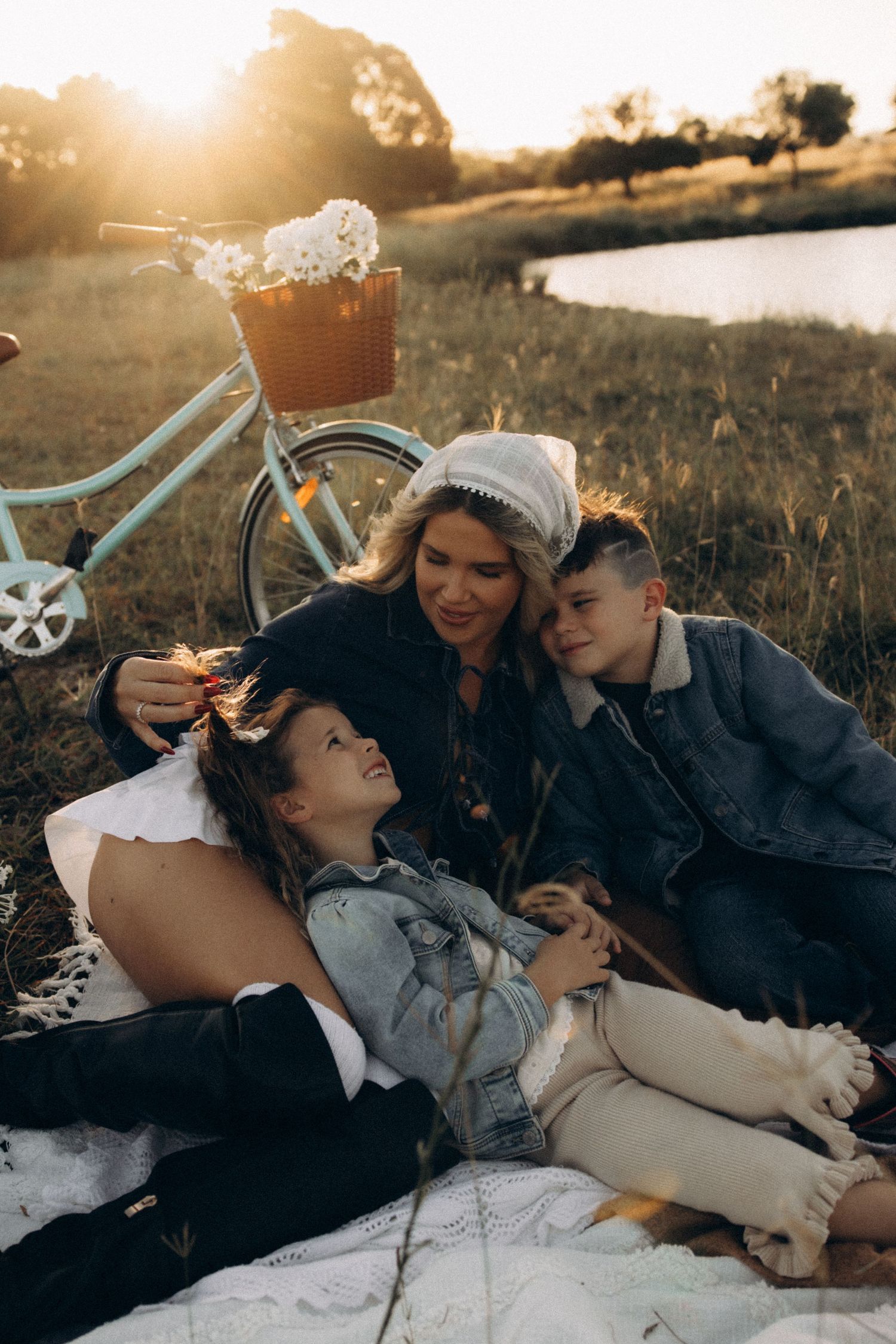 A couple relaxes on a blanket during a countryside picnic at golden hour.