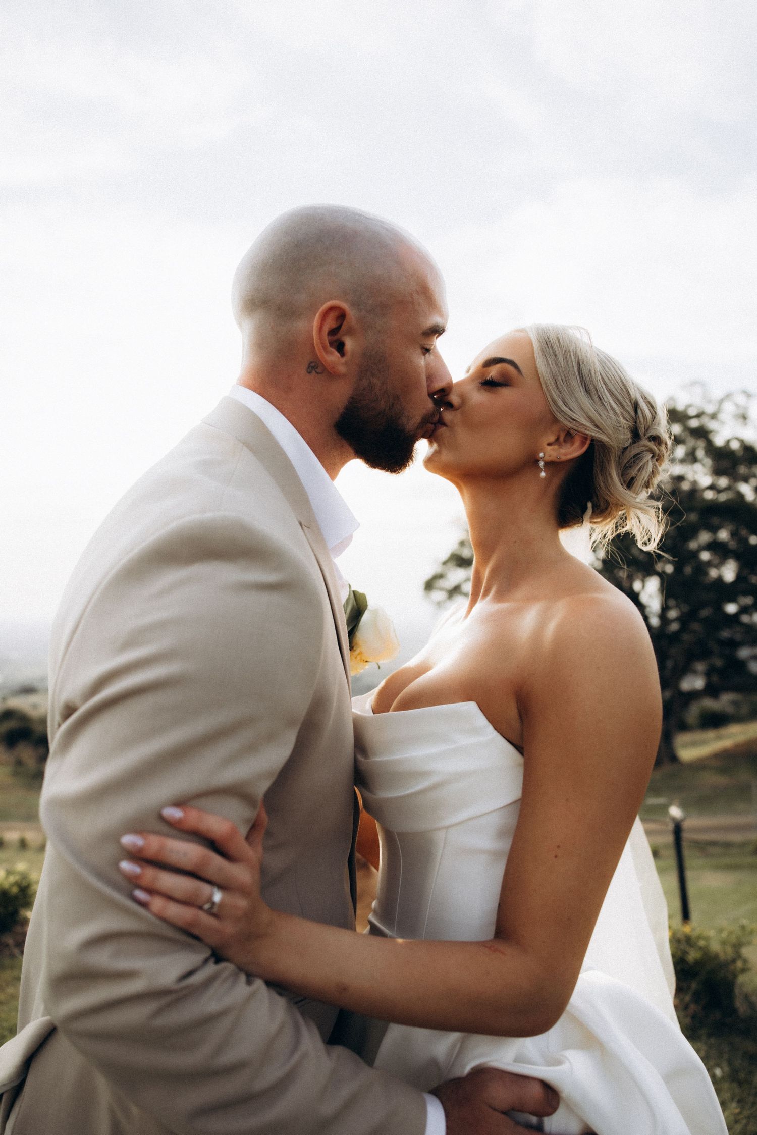 Romantic wedding couple embracing outdoors in natural lighting.