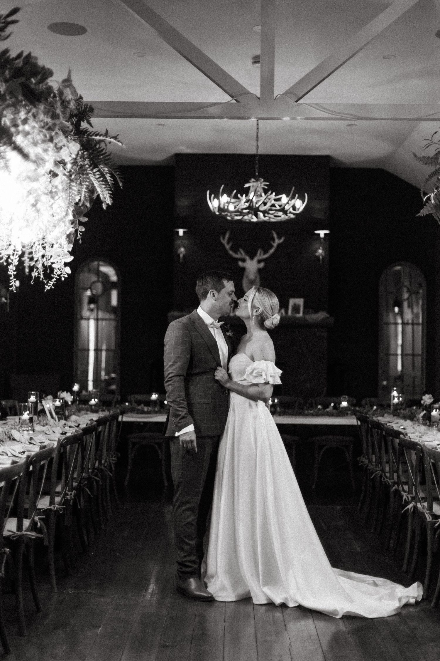 Wedding couple dancing in a dimly lit reception hall with elegant table settings.