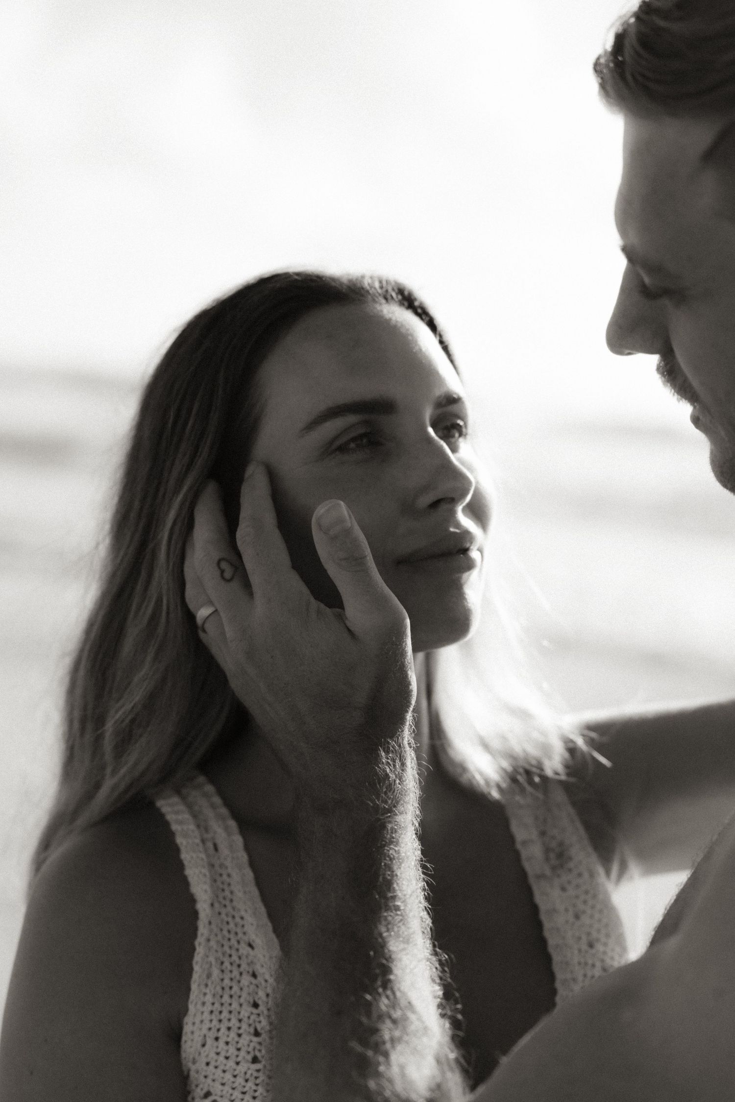 An intimate black and white close-up portrait of a couple gazing at each other.