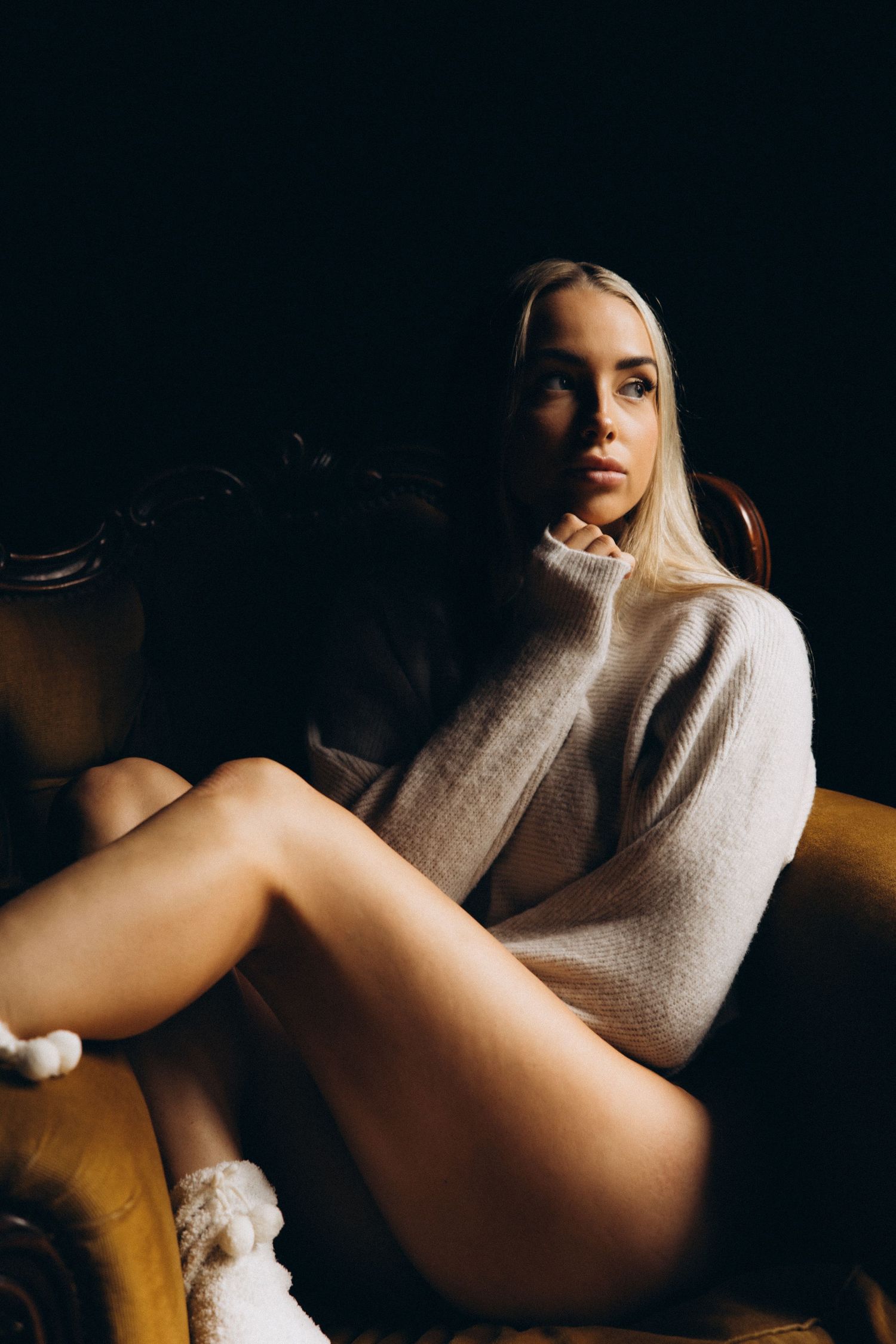 Moody boudoir sequence with white sweater against dark background.