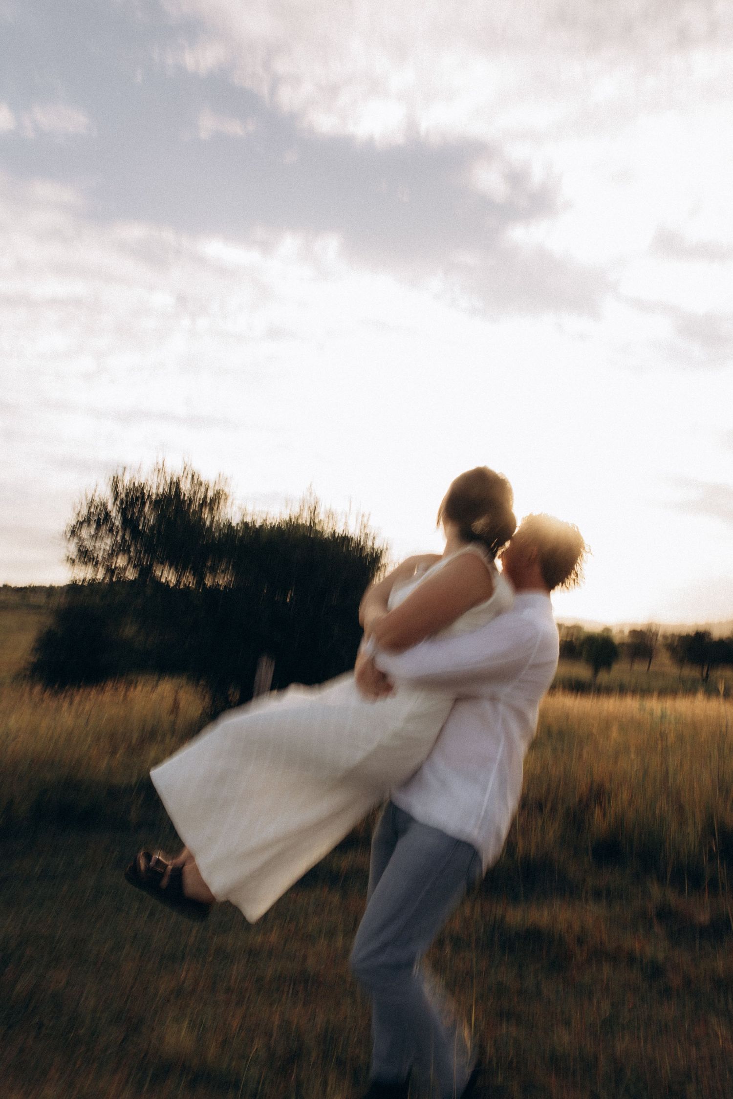 A romantic dance lift photographed in a field at sunset.