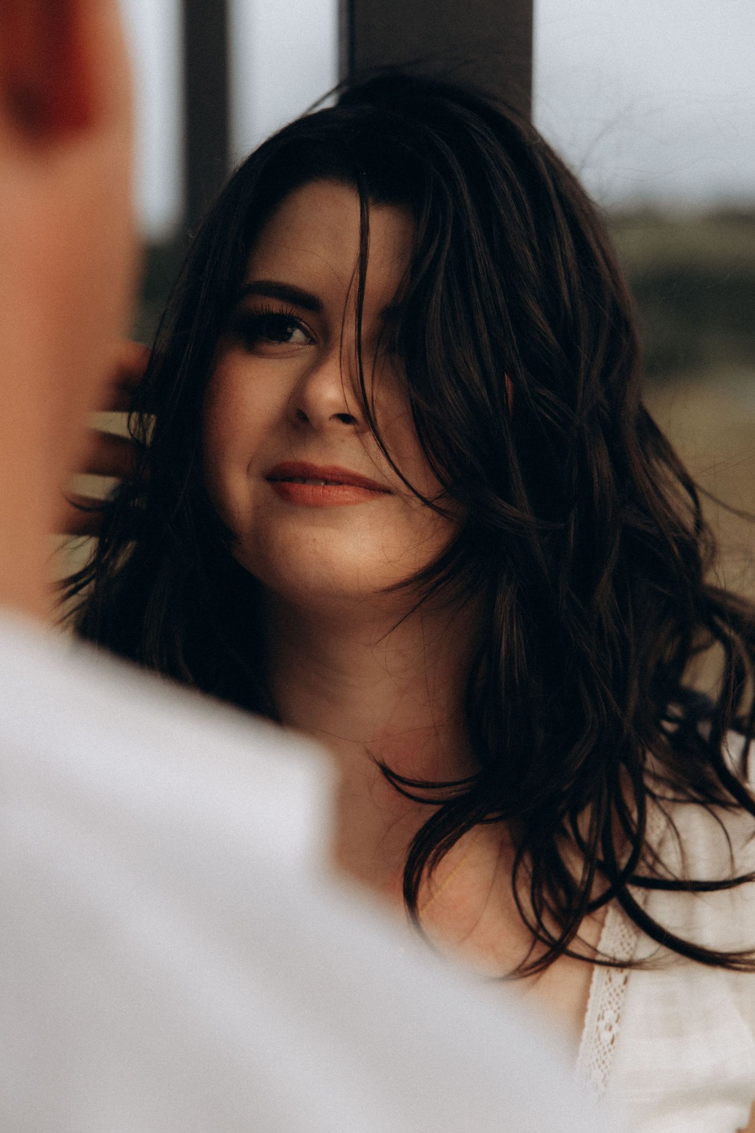 Close-up portrait of dark hair blowing in the wind against a blurred background.