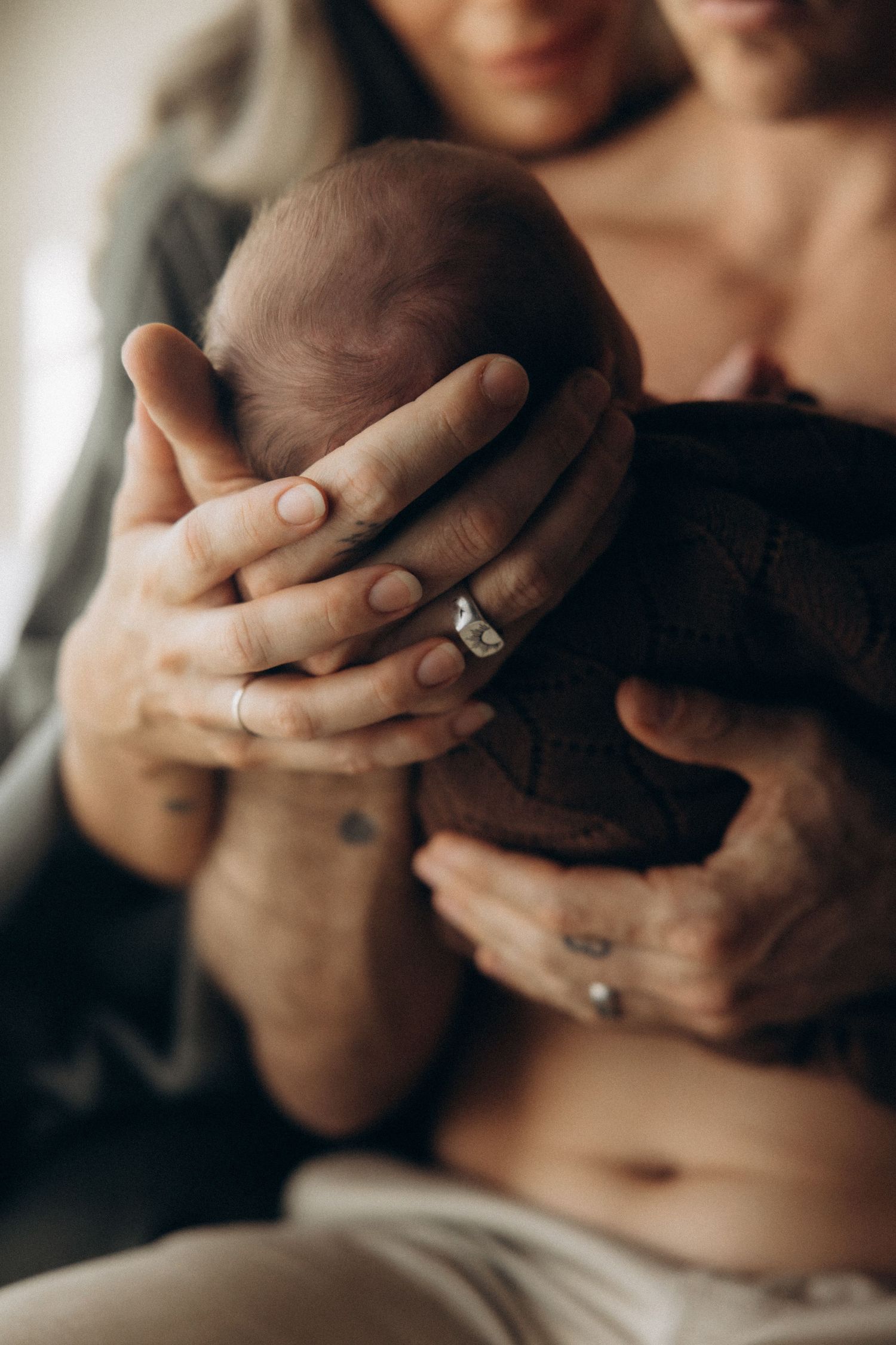 Close-up of hands with wedding rings intertwined in intimate gesture.