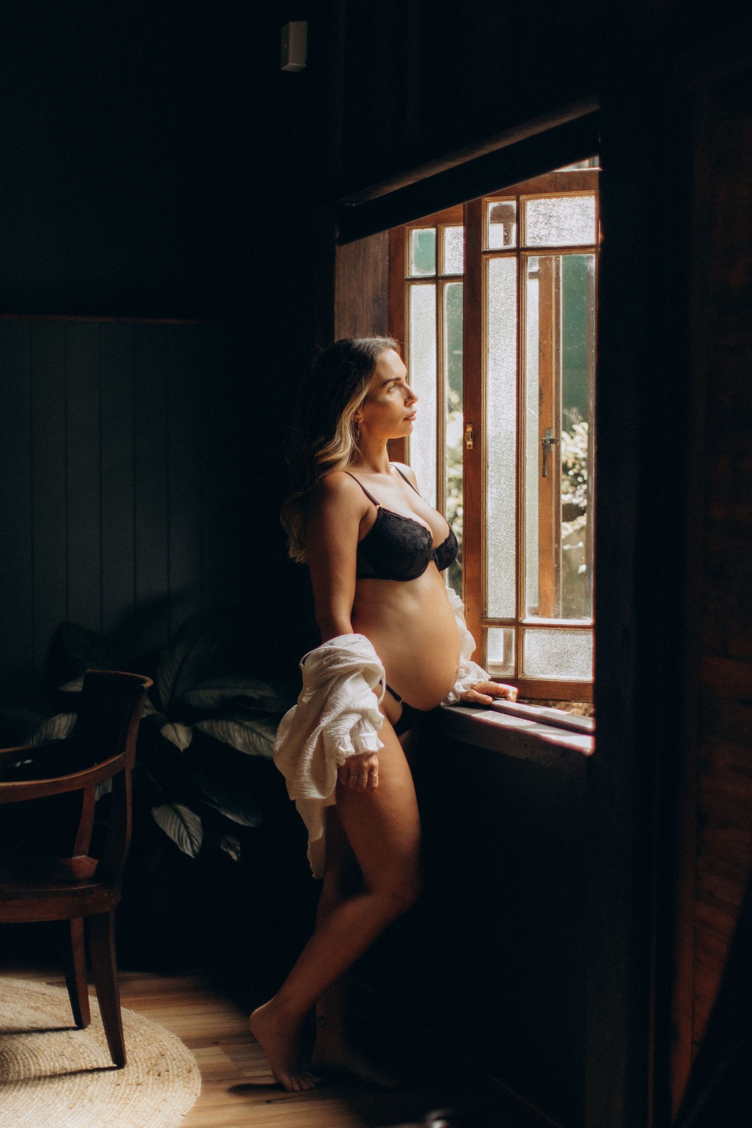 A series of moody boudoir photos showing a figure silhouetted against natural window light in a dark room.