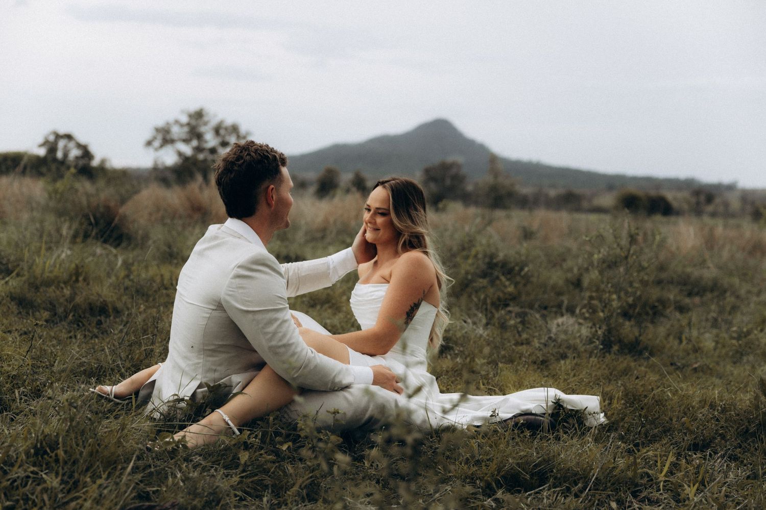 Romantic photoshoot in a field with horses and mountains in the distance.