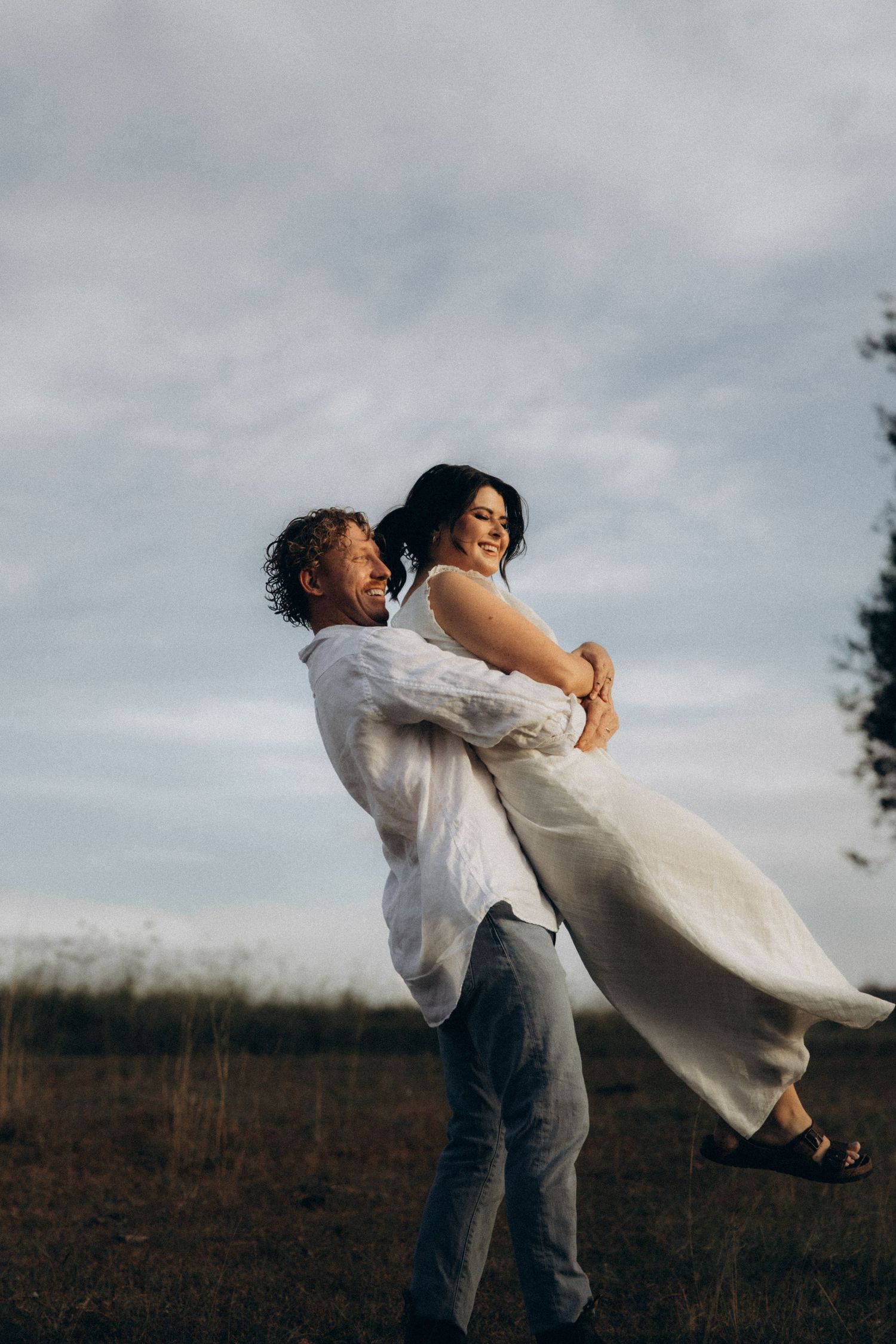 A joyful dance lift captured in a field during golden hour.