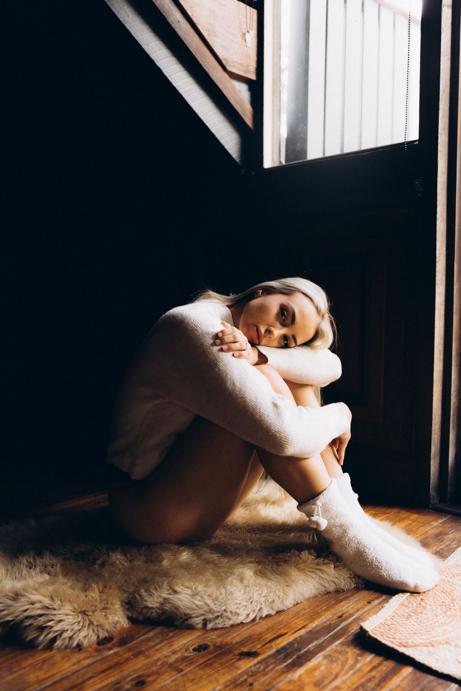 Cozy winter portrait on wooden floor with sheepskin rug and natural window light.
