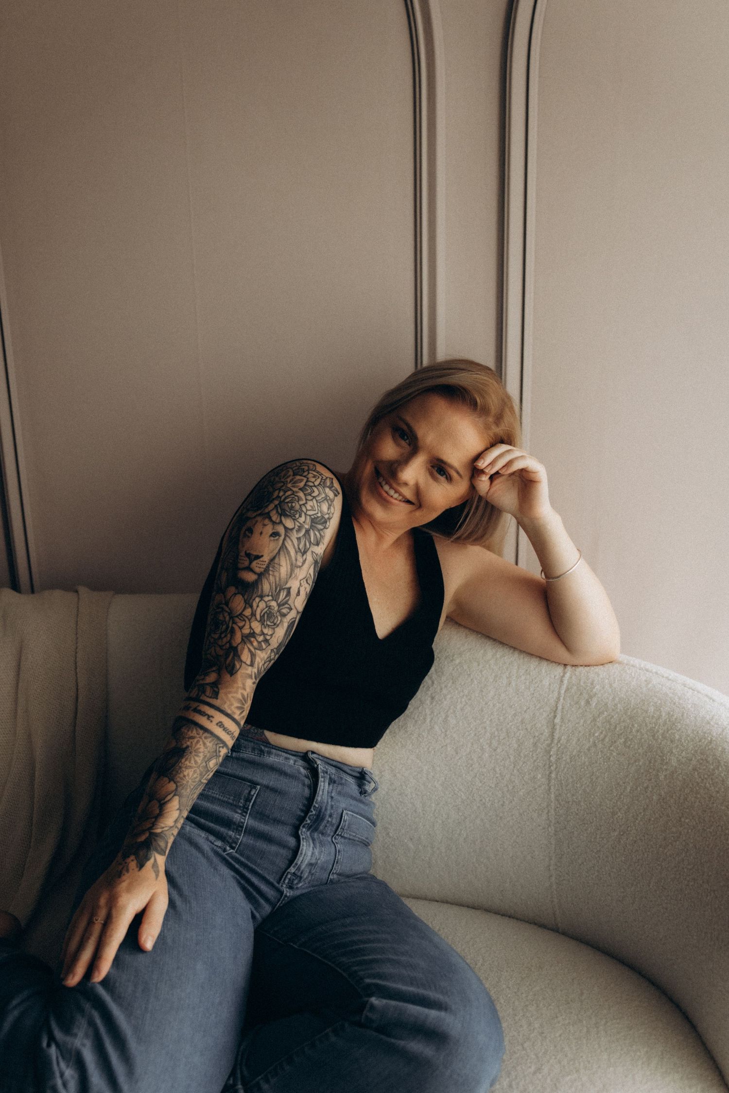 Artistic portrait series showing person with tattoos resting on white couch.