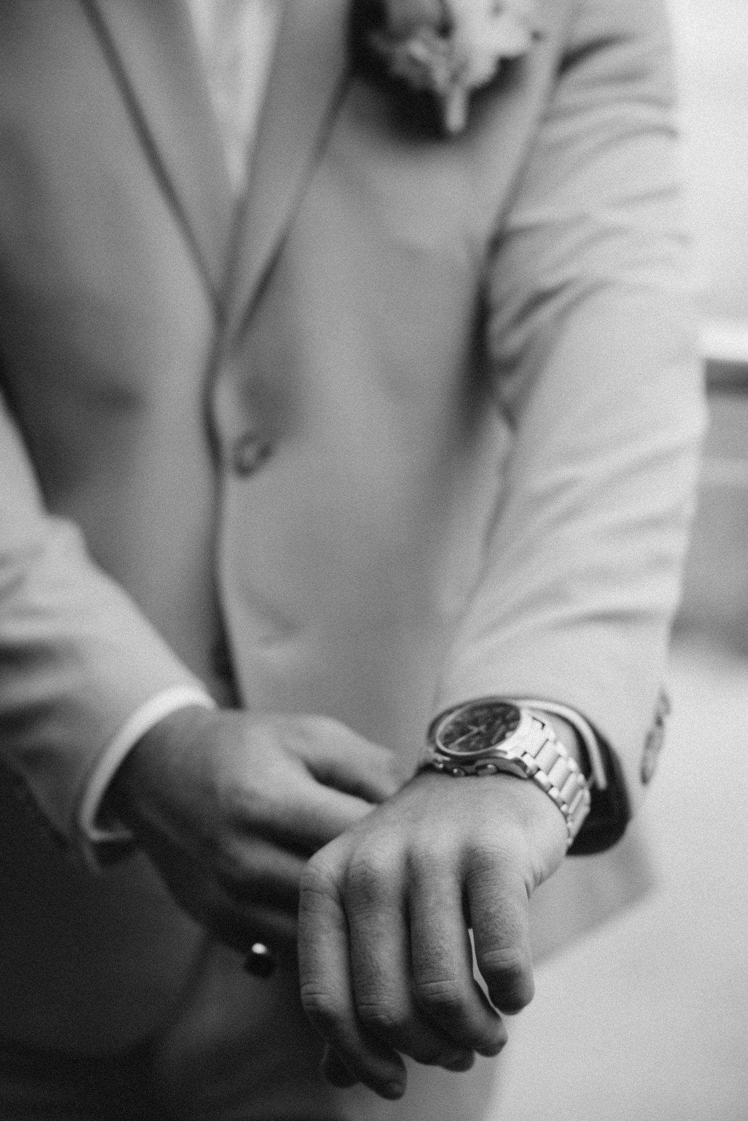 Black and white detail shots of hands with watch and formal attire.