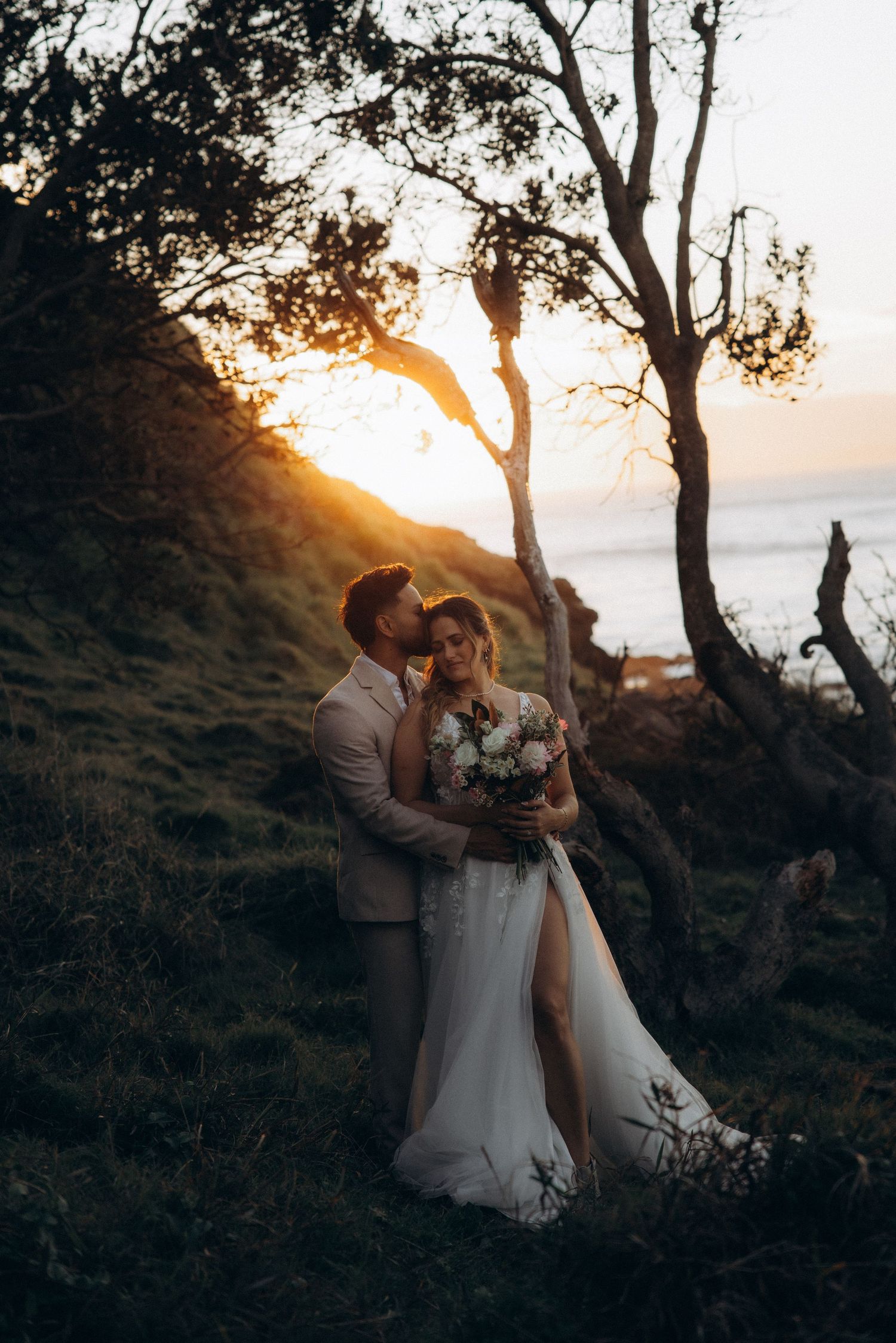 Romantic sunset wedding photos captured against scenic coastal backdrop.