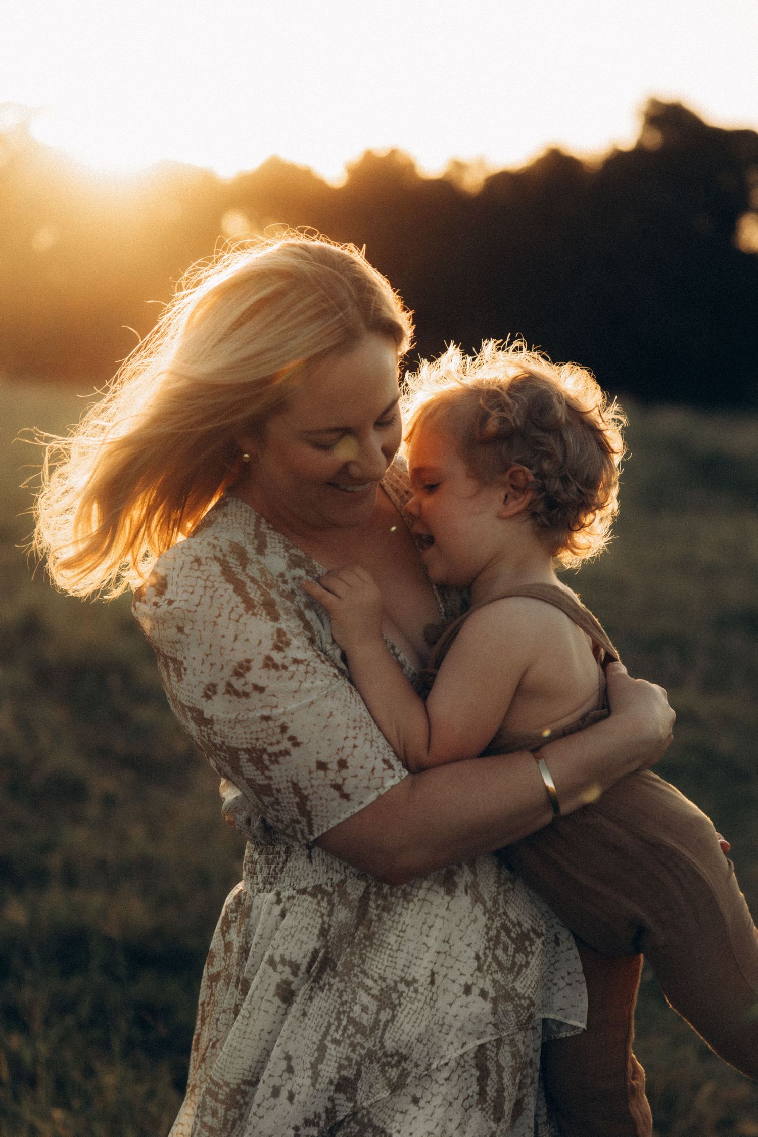 Loving family embrace photographed in a golden field at sunset.