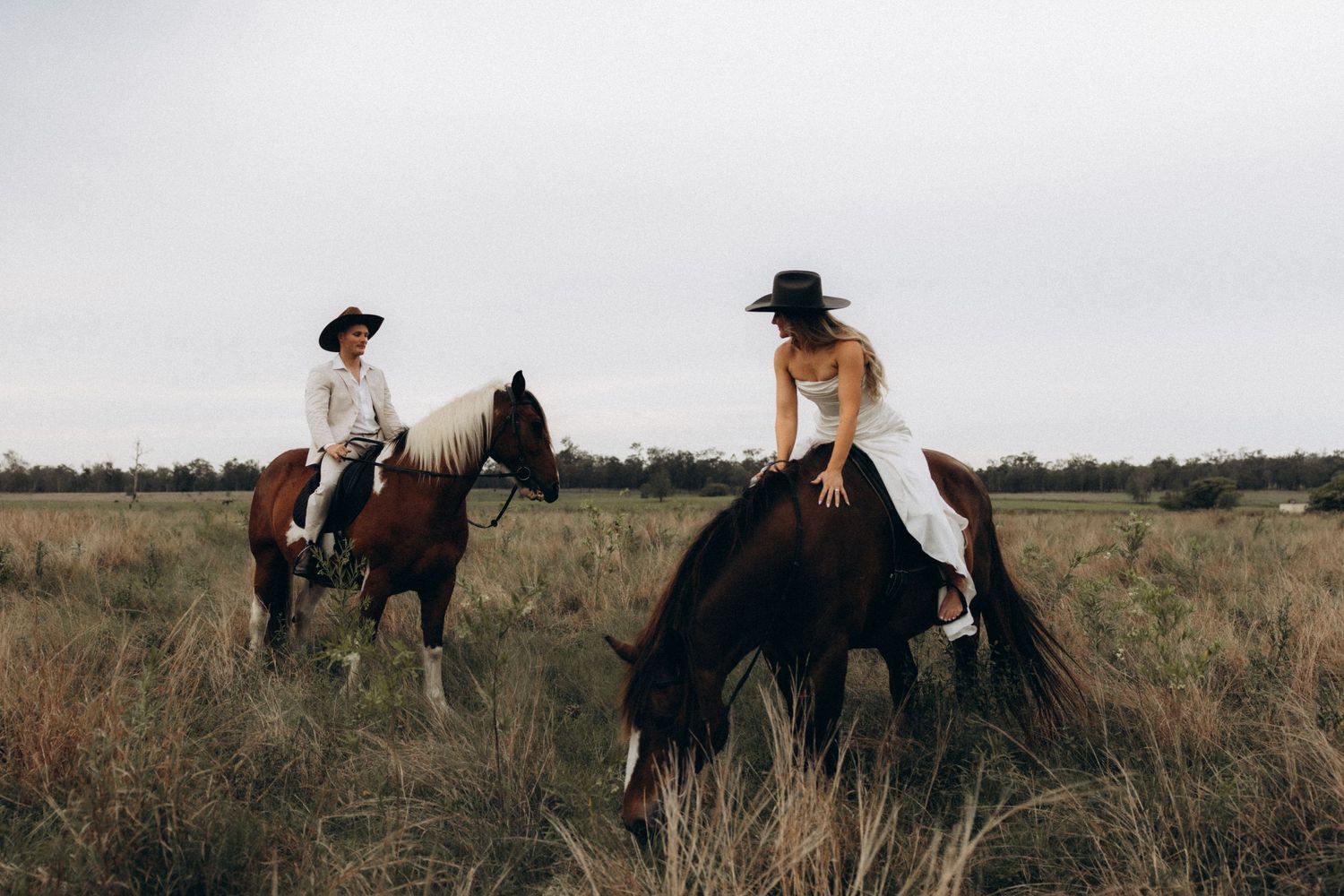 A romantic wedding photoshoot in a rustic field with a brown and white horse.