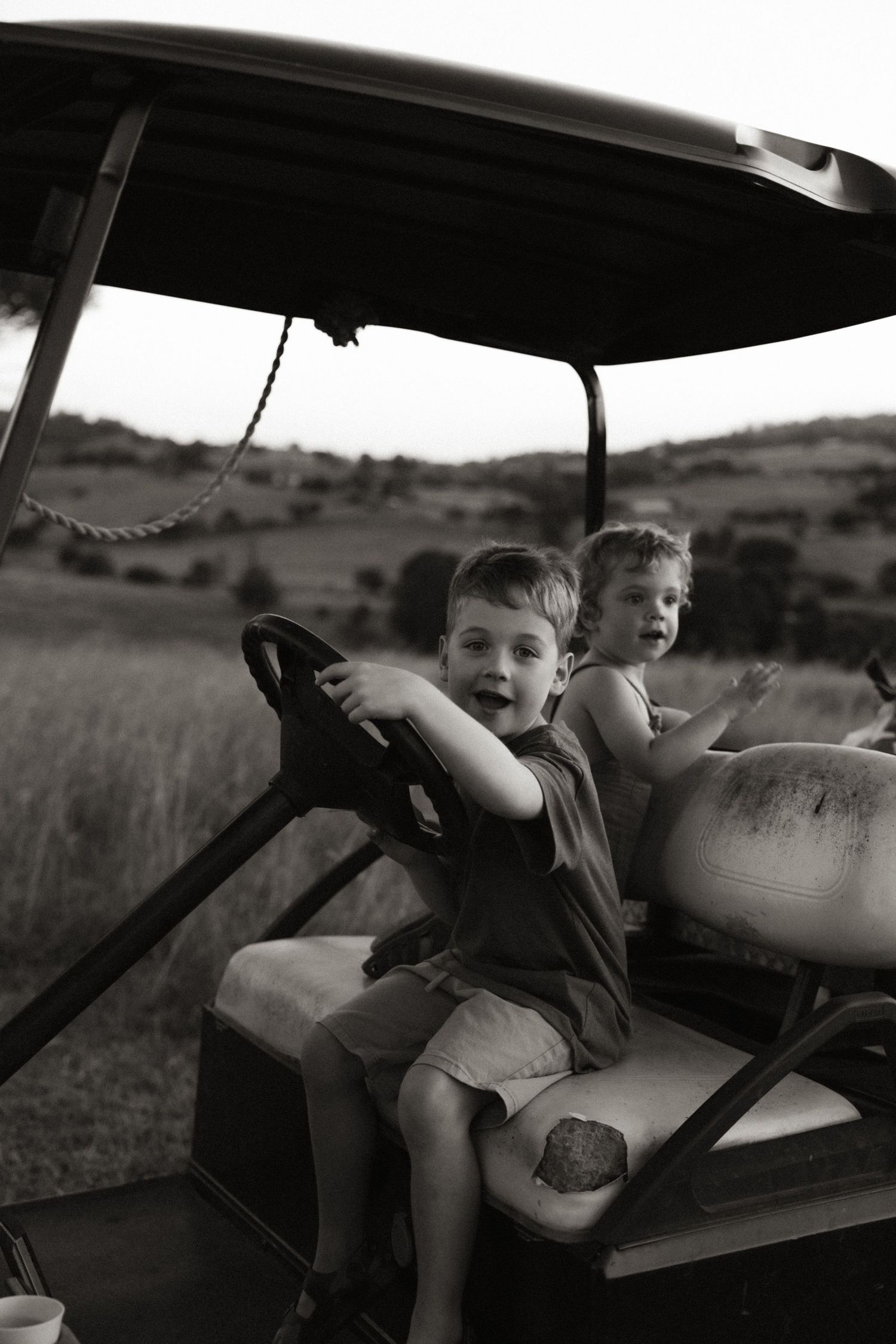 Children enjoying a ride in a golf cart across a scenic field.