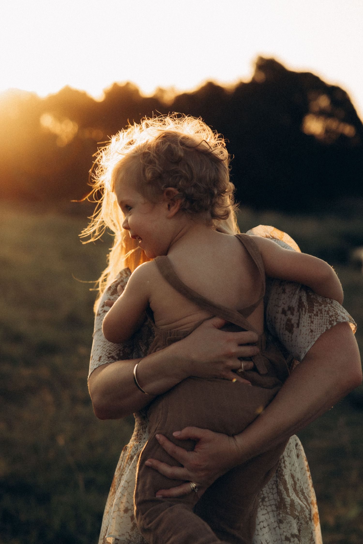 Tender family moment captured in silhouette against a sunset sky.