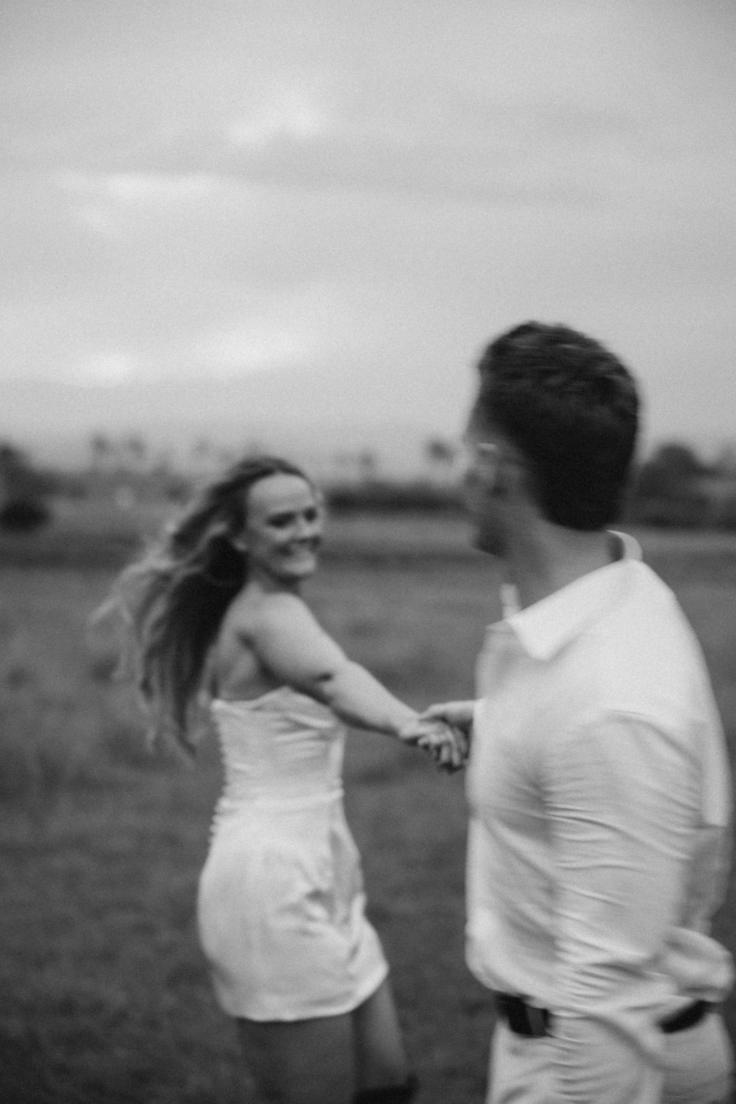 A couple shares a playful moment in a field during their wedding photoshoot.