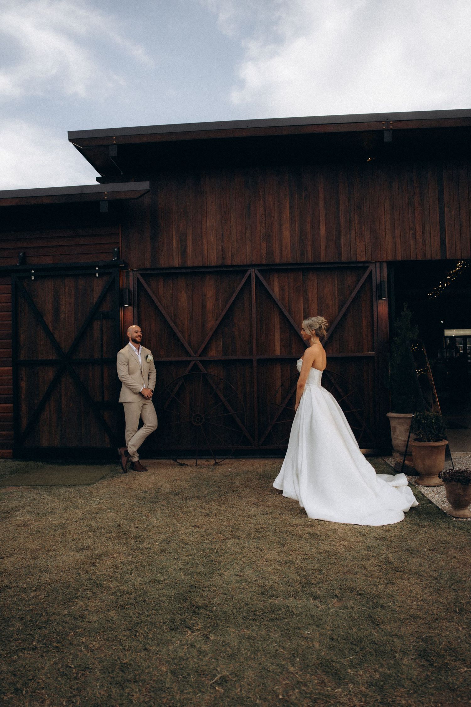 Wedding couple walks along a rustic barn exterior in a candid sequence.