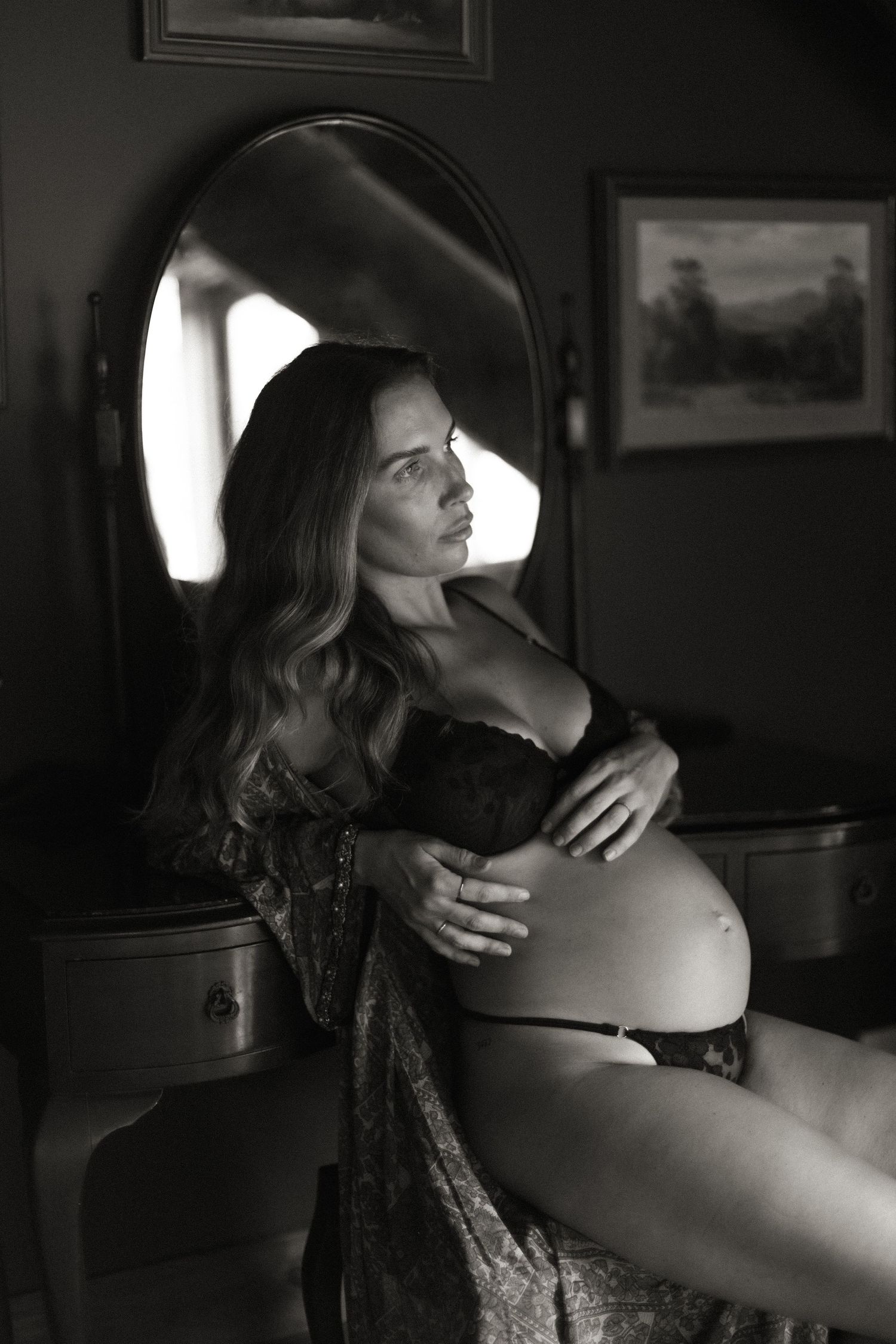 Dramatic black and white boudoir photo with natural window lighting.