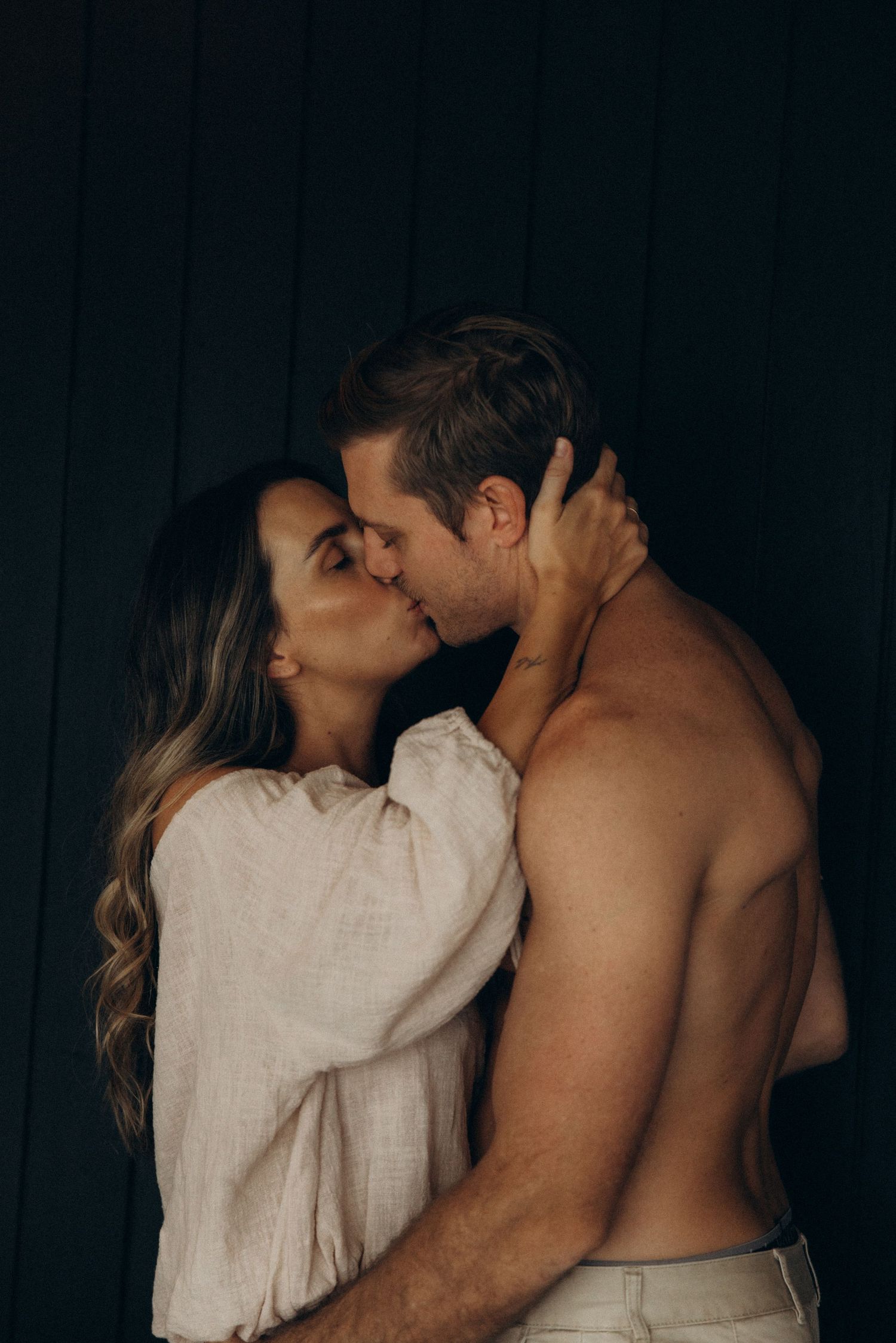 Intimate moment captured against dark walls in warm lighting.