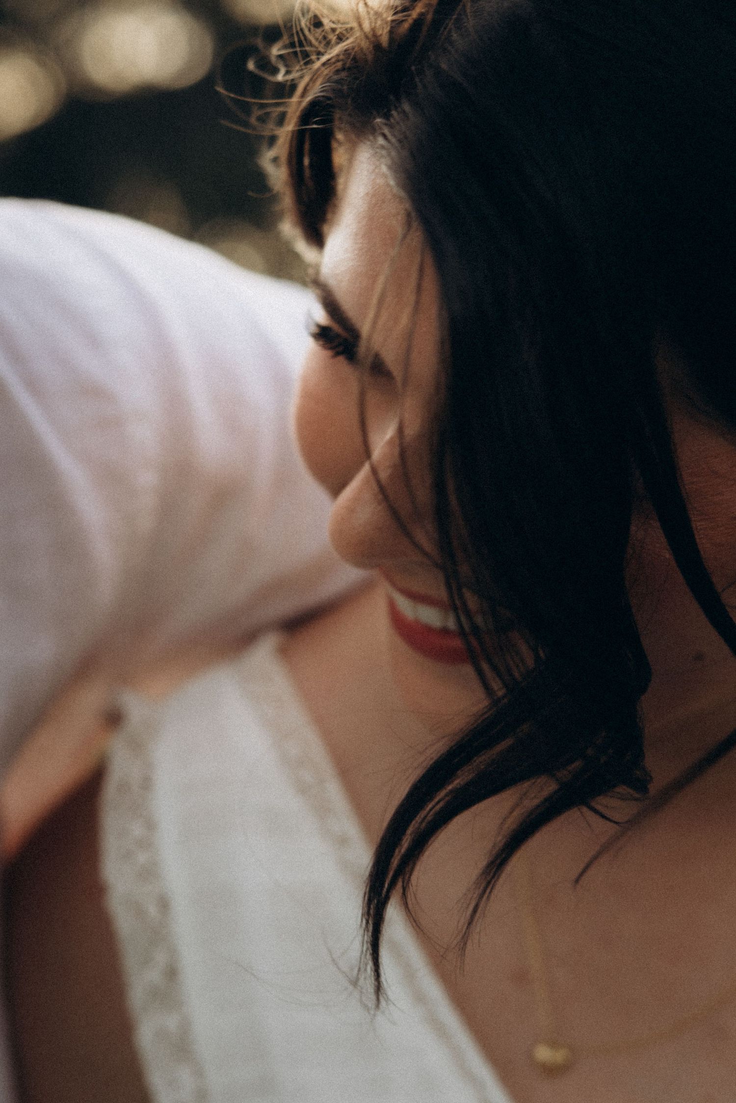 Artistic close-up detail of a white wedding dress and dark hair.