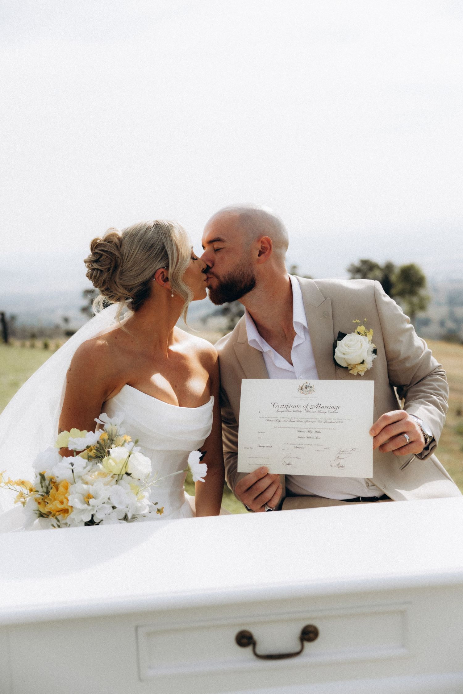 Newlyweds sharing intimate moments while holding their marriage certificate.