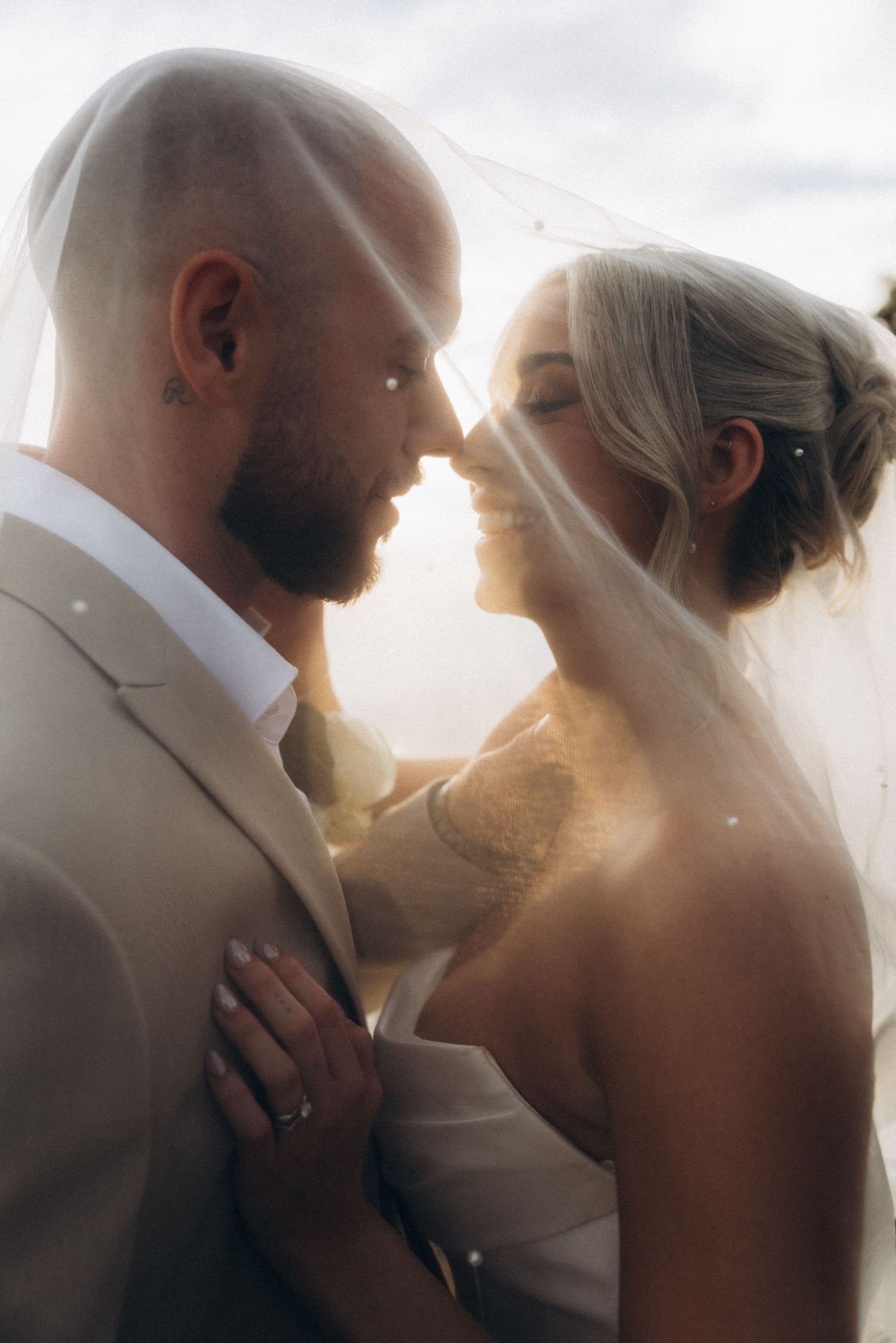 Intimate wedding portrait silhouettes against soft sunlight.