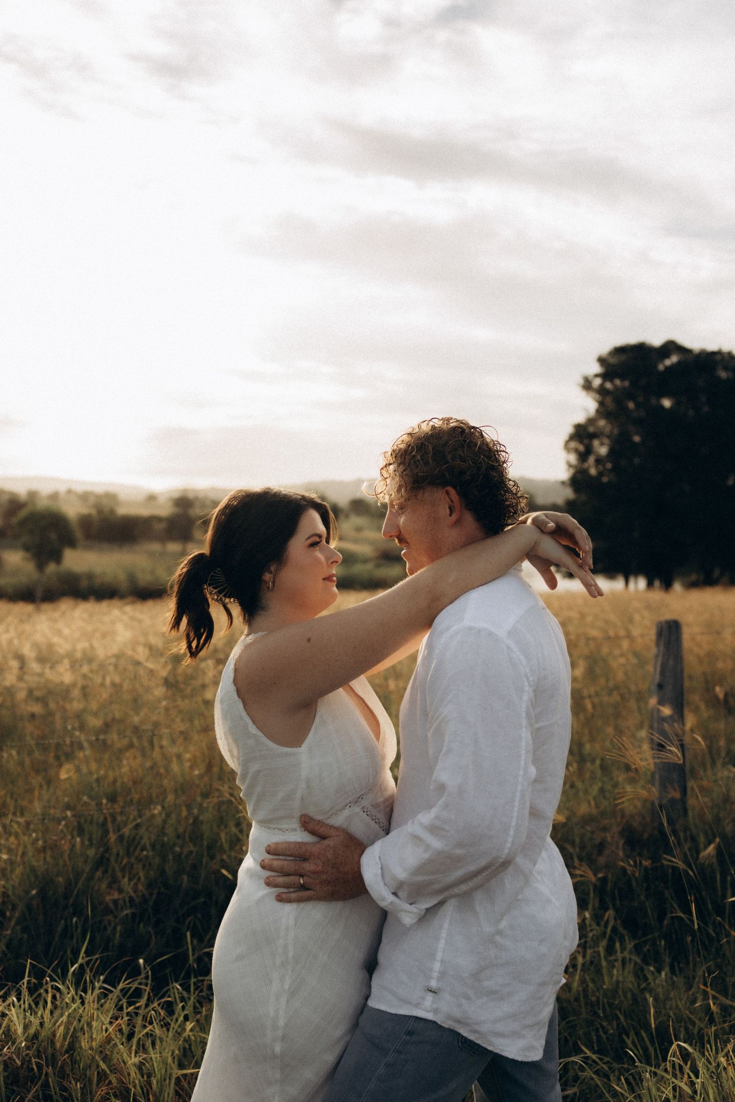 Loving couple shares romantic moment in rustic outdoor field.