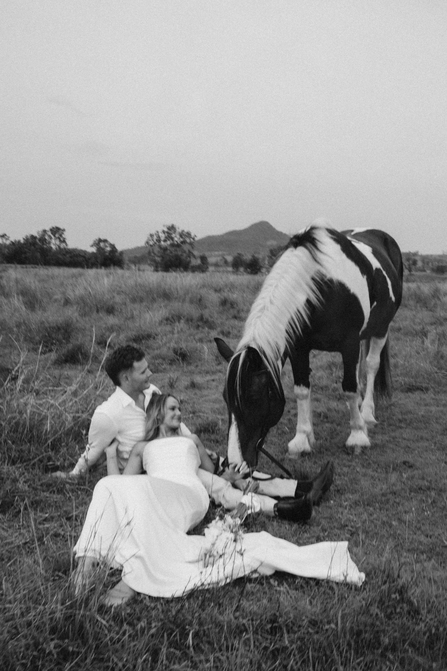 People relaxing on blankets next to grazing horses in a field.