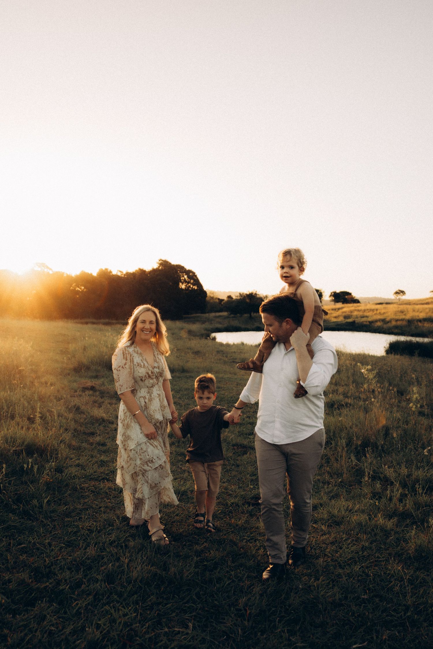 Family members walk together across a grassy field at sunset.