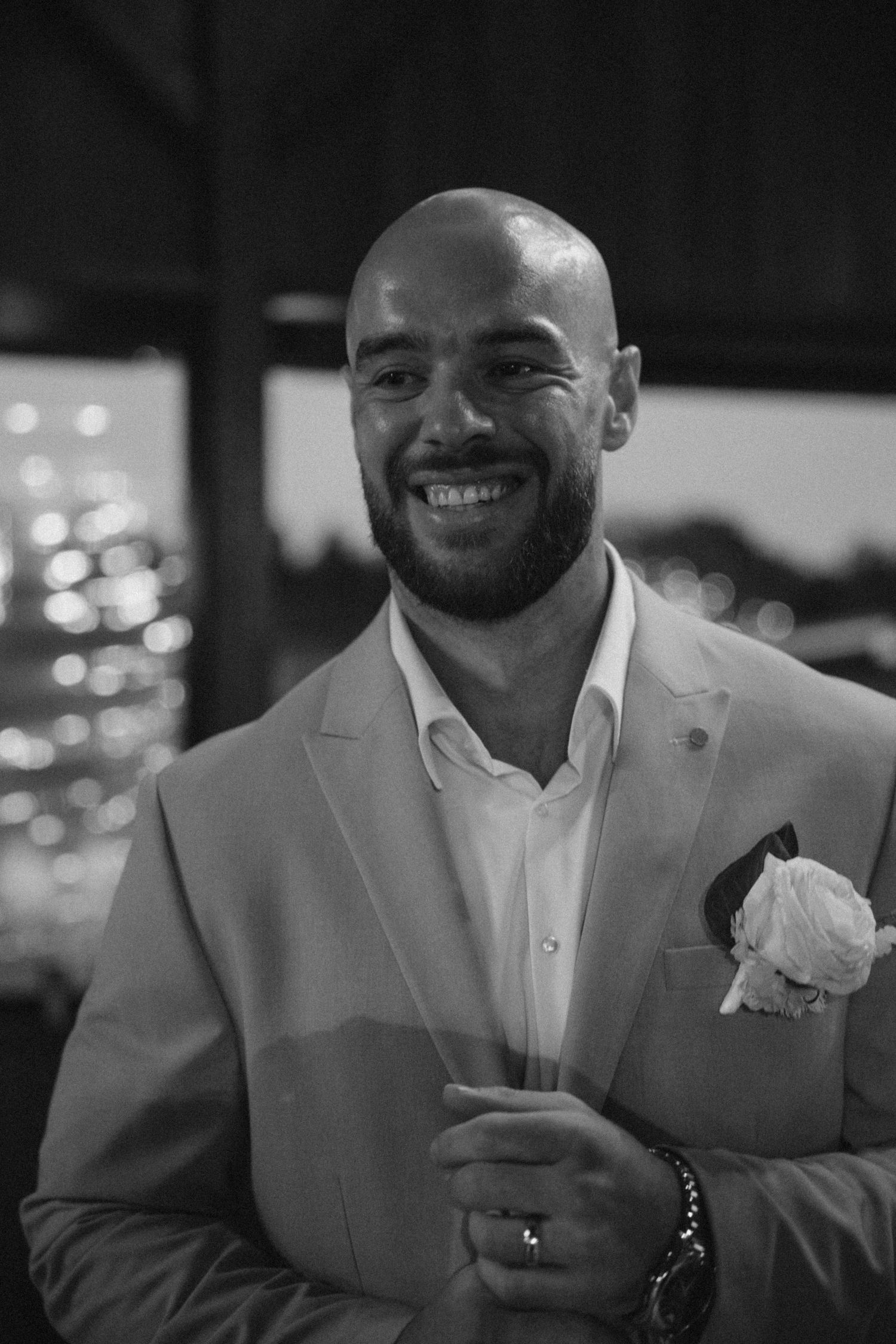 A person wearing a light colored suit and boutonniere at a formal event.