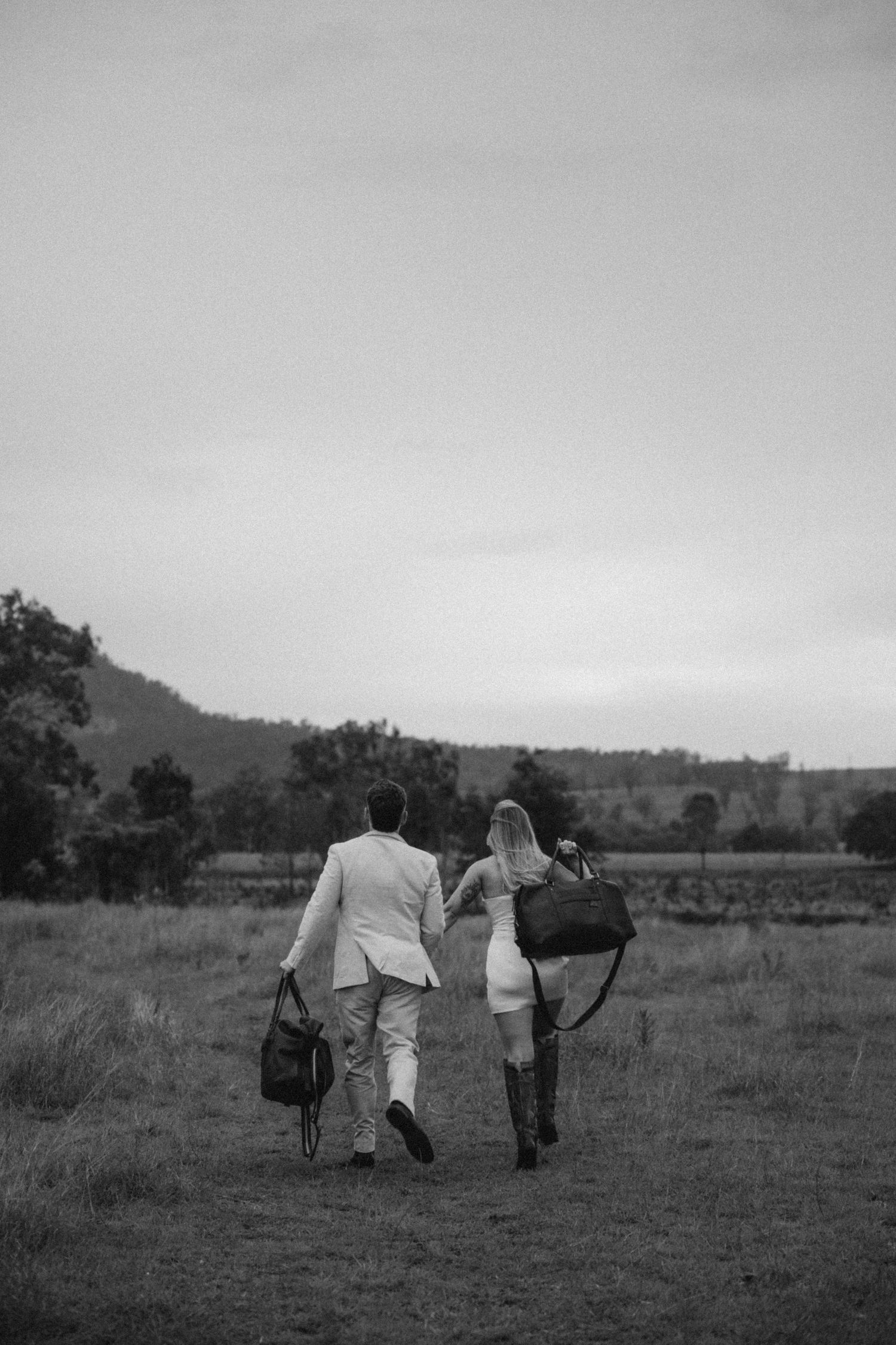 A distant view of a couple walking with their horse across a rural landscape.