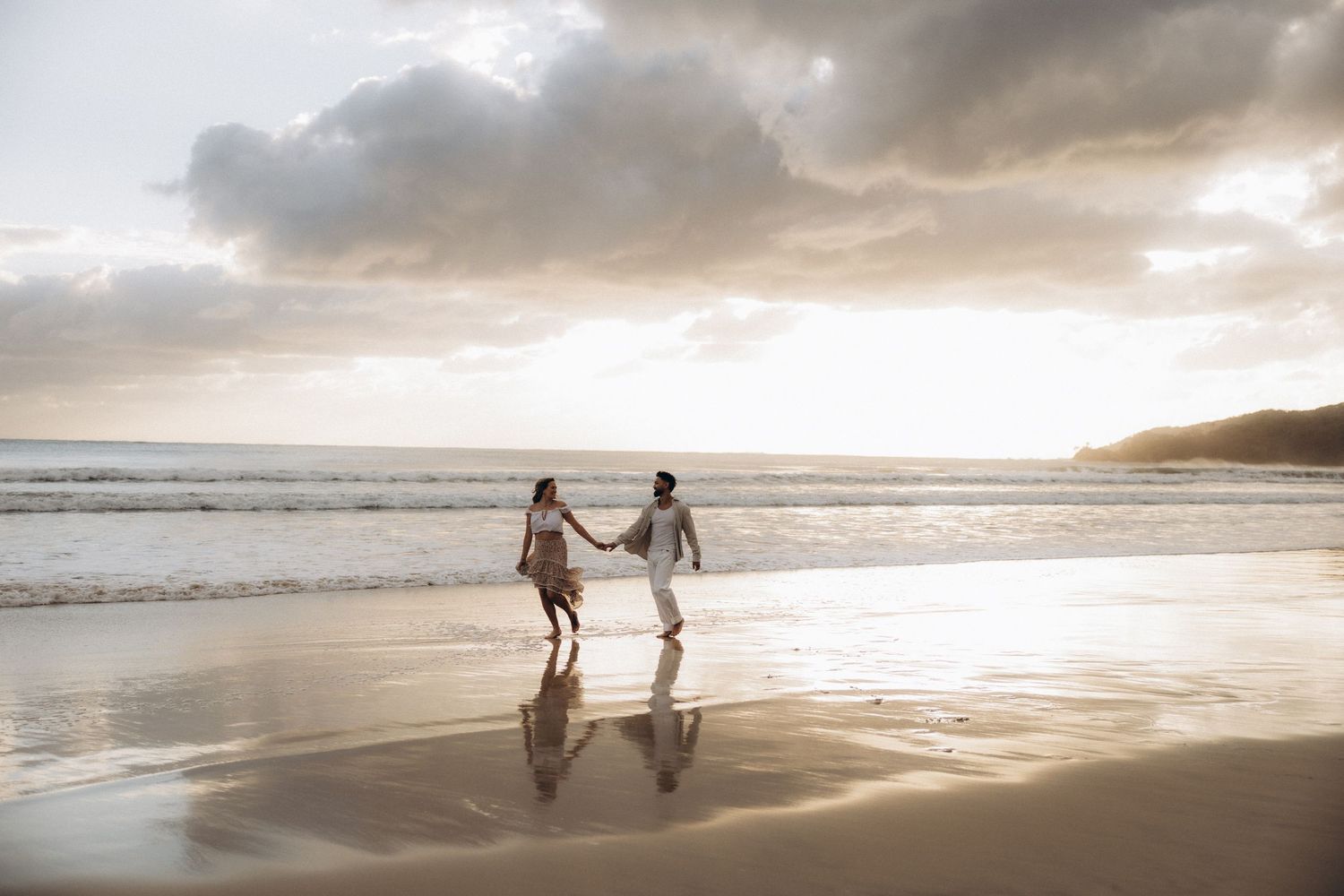 Dreamy beach scene at sunset with golden light reflecting on wet sand.