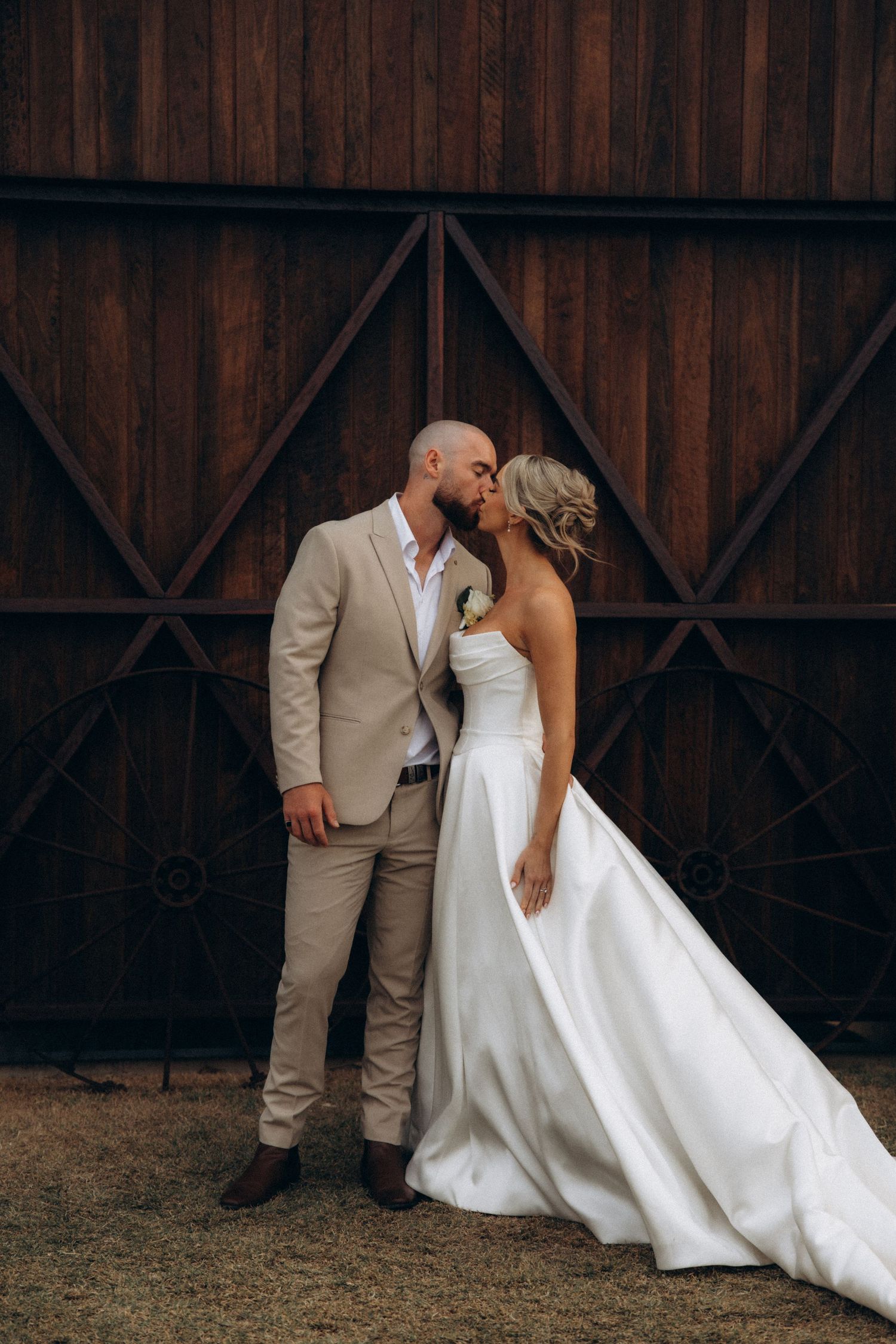 Romantic wedding couple shares an intimate moment against a rustic barn backdrop.