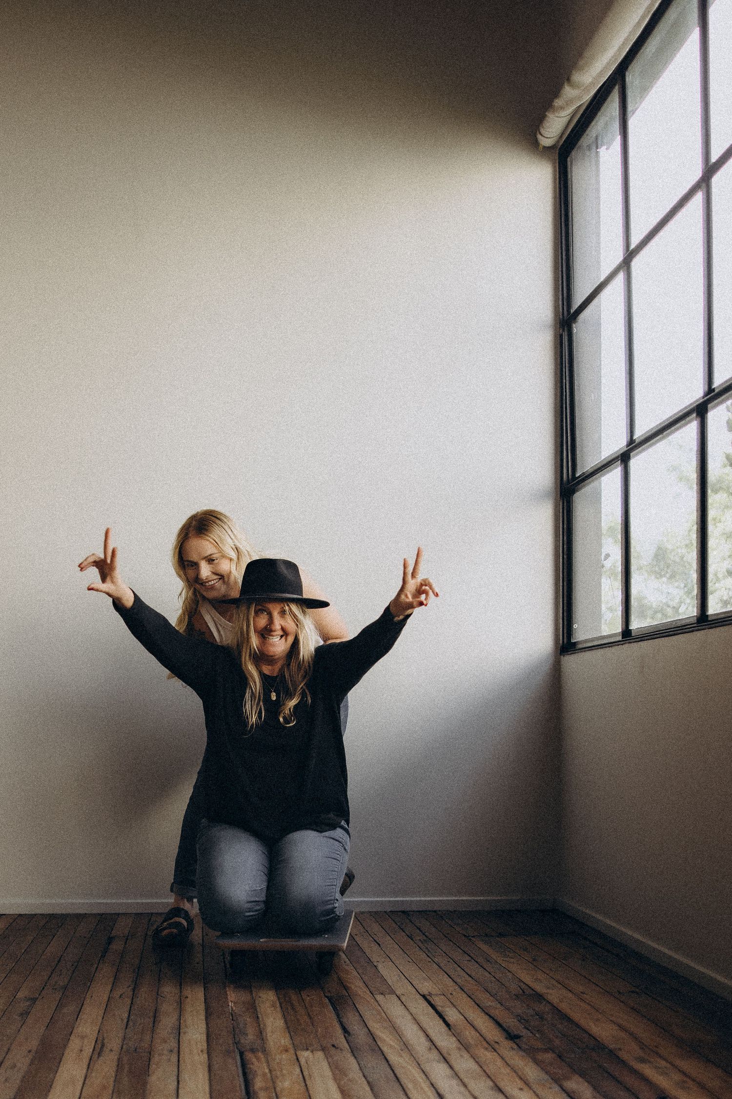 Creative studio portraits showing joyful poses on hardwood floor.