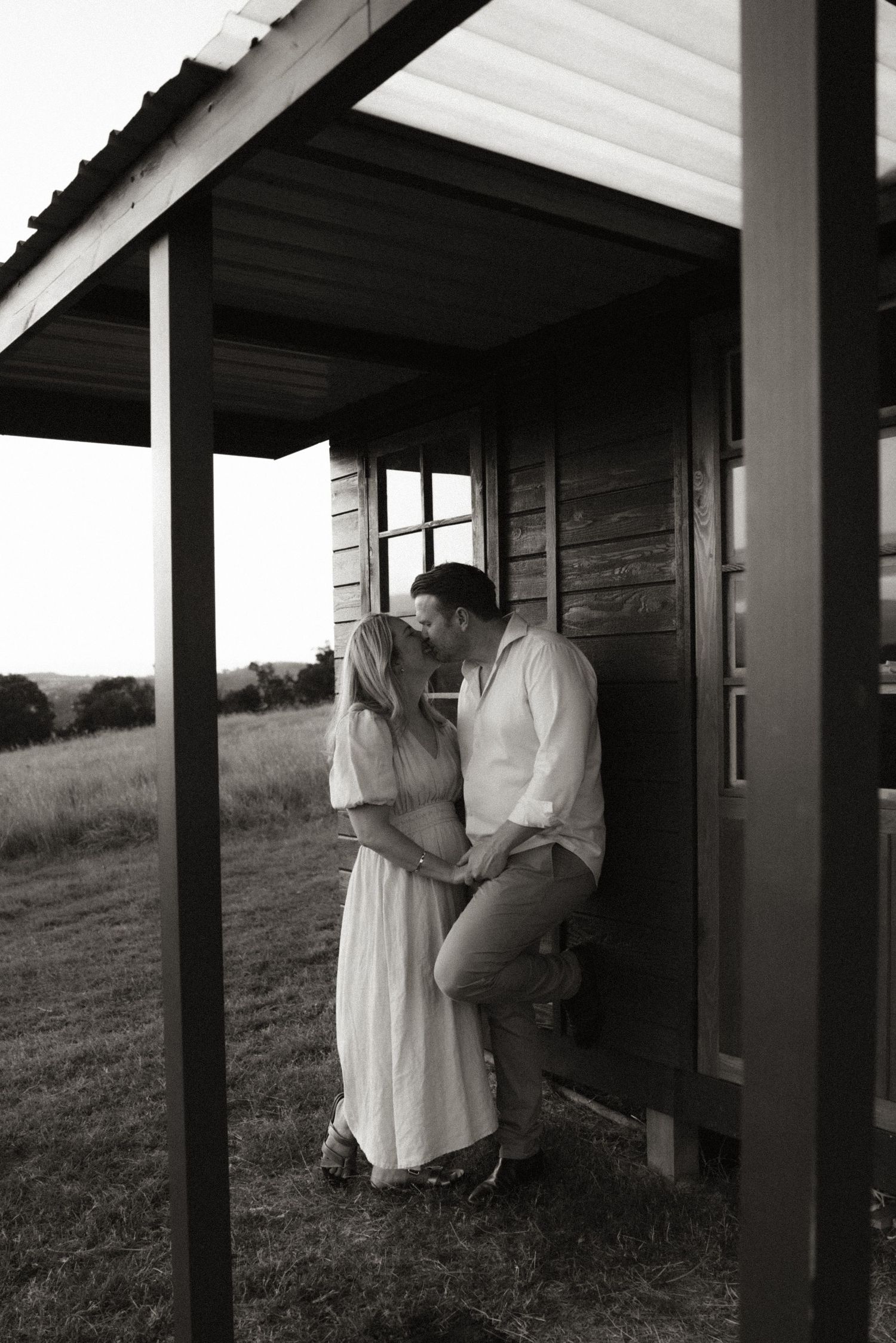 Black and white photos of a couple sharing intimate moments on a rustic porch.