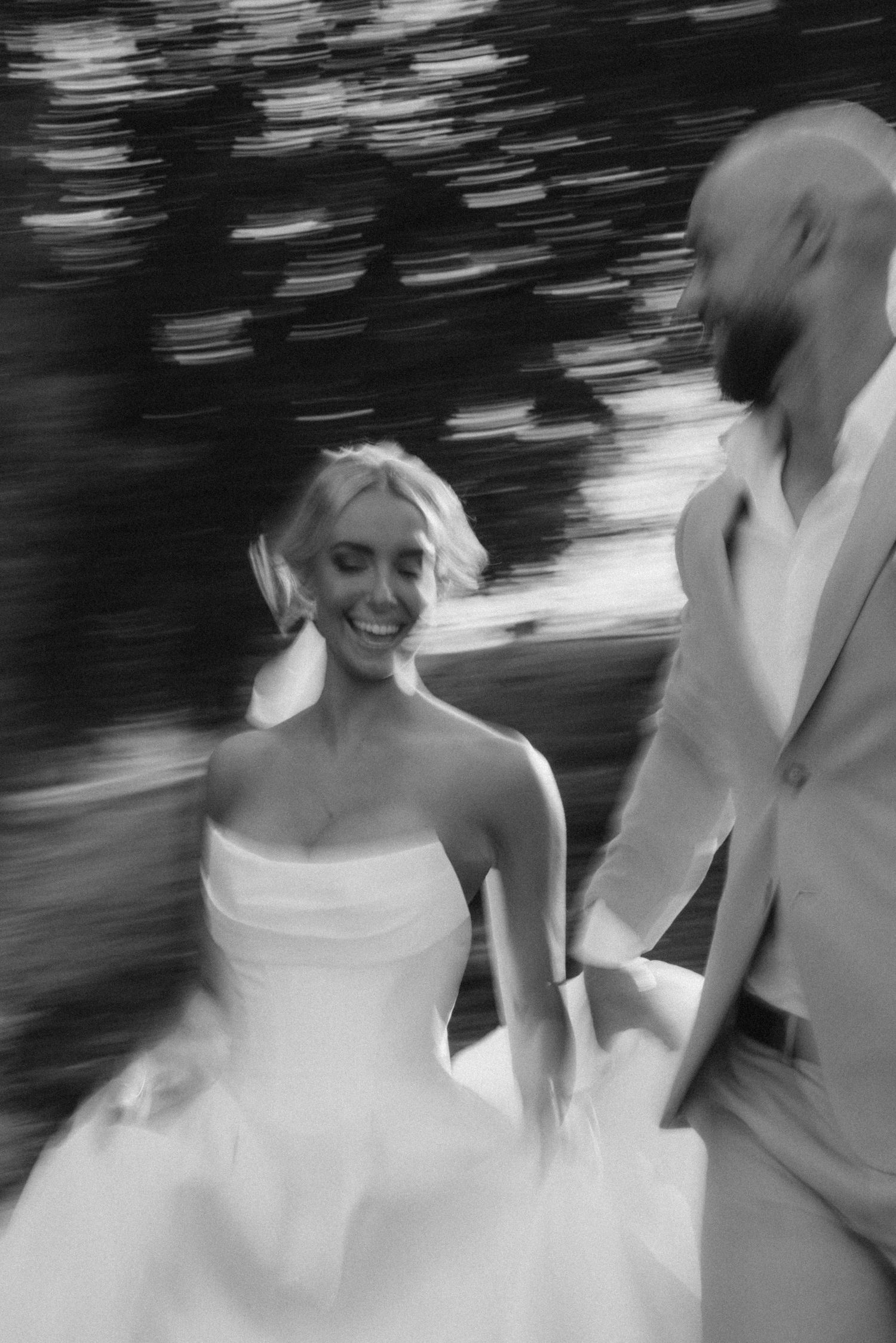 A black and white motion-blur wedding photo capturing movement and joy.