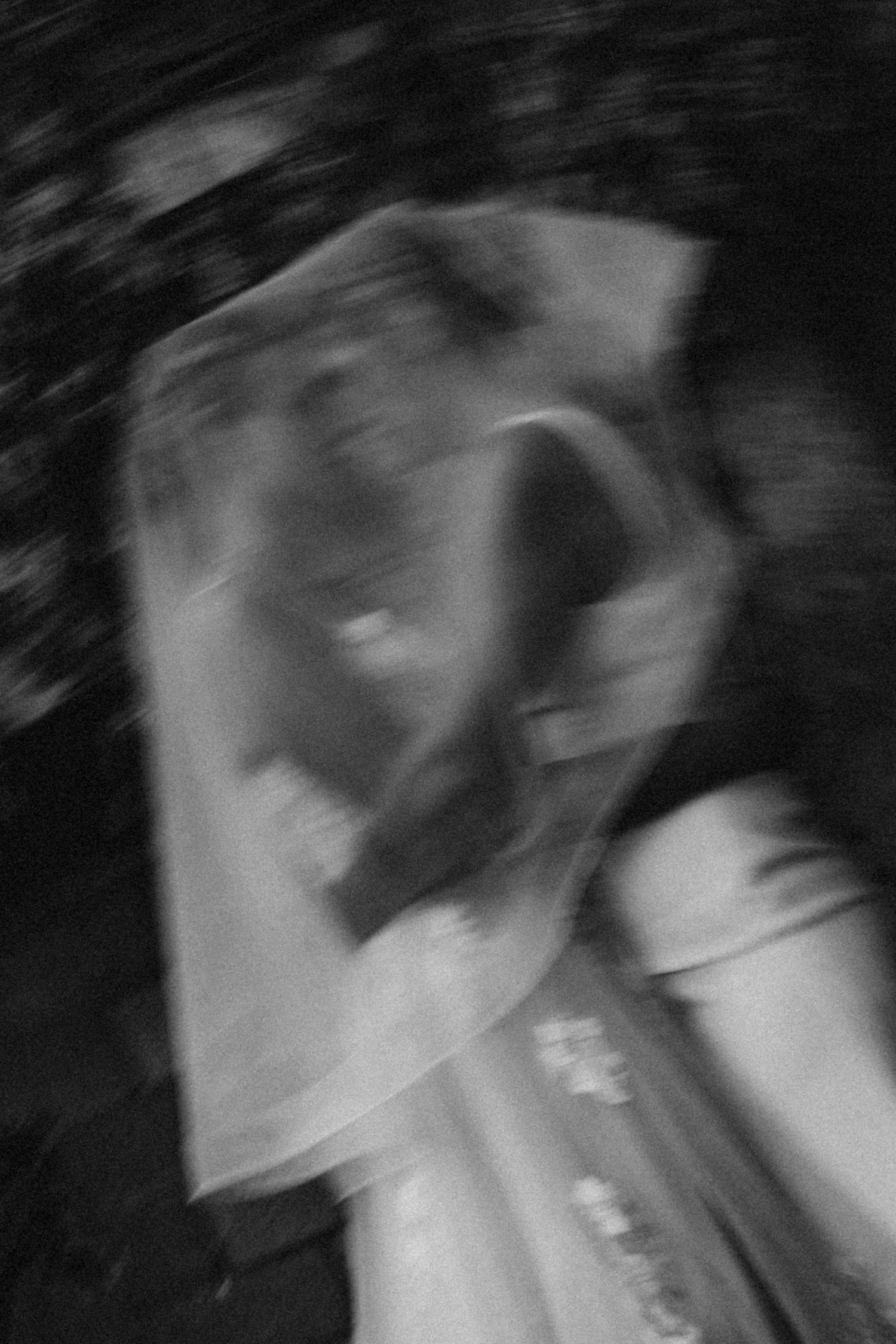 Blurry black and white photo of a bride in a wedding dress and veil, creating a dreamy, motion-blur effect.
