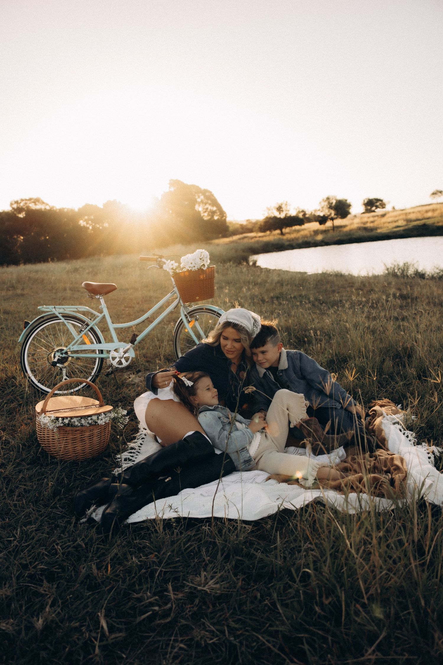 A romantic sunset picnic scene with a vintage bicycle and wicker basket in a grassy field.