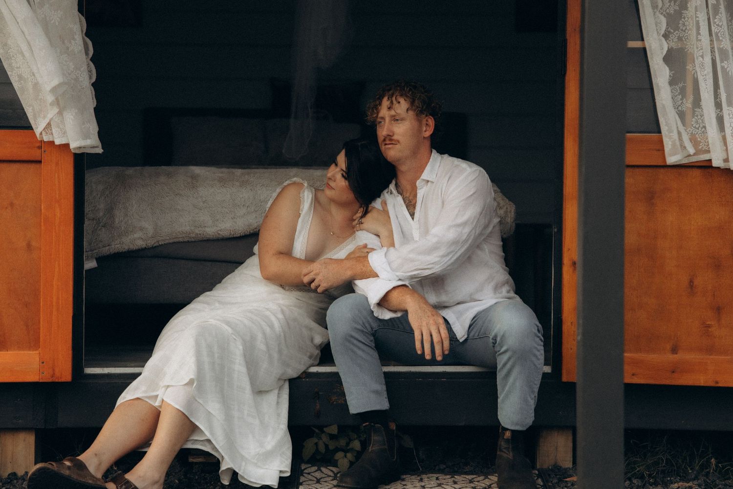 Two people share a relaxed moment sitting on a rustic cabin porch.