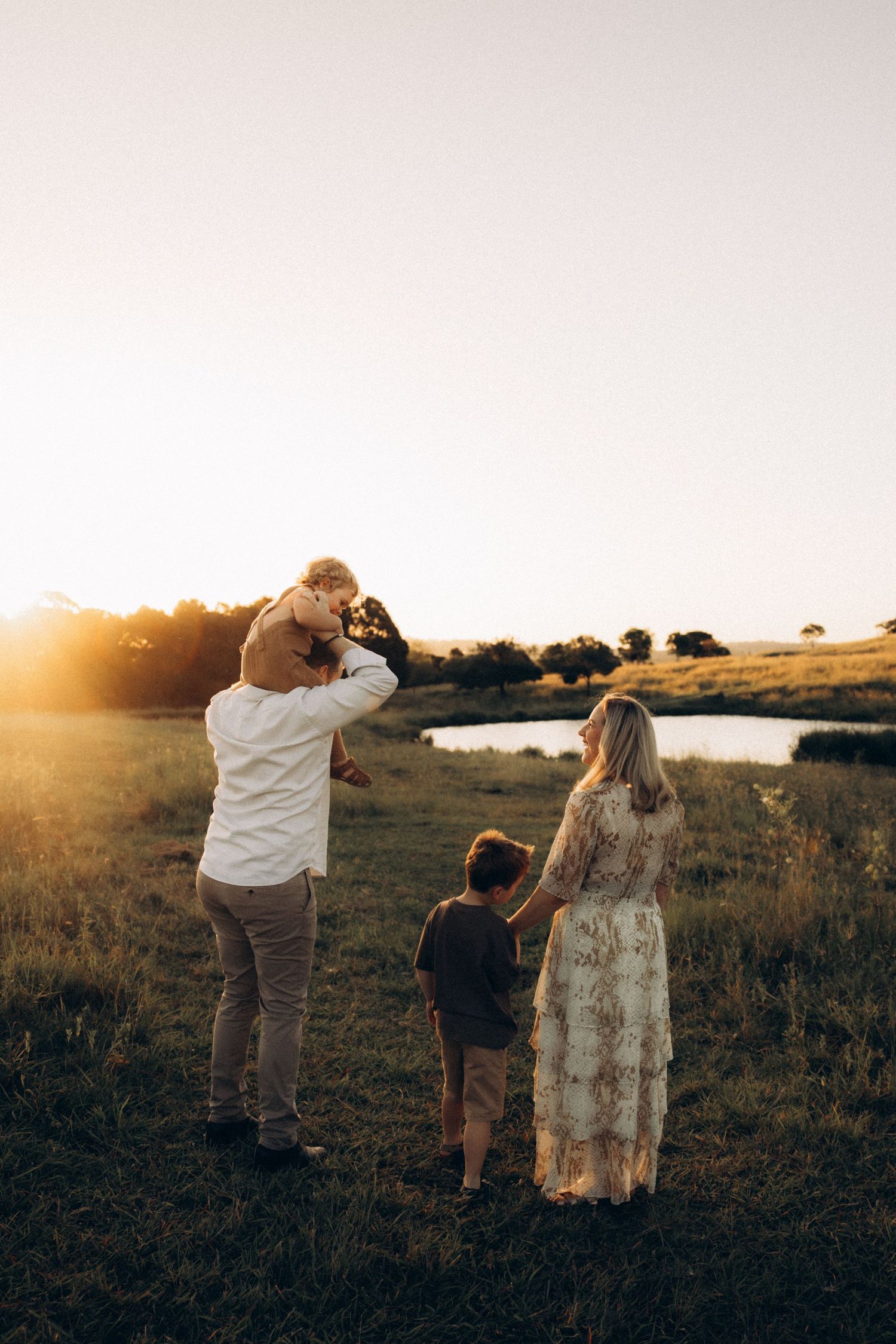 Family members stand together in a field during golden hour.