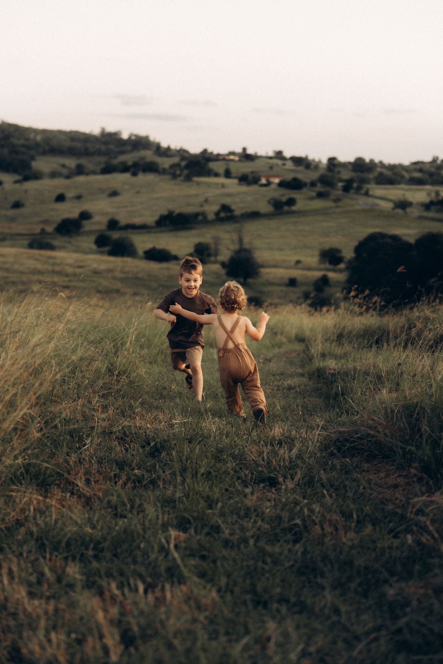 Children run and play together in a vast field during golden hour.