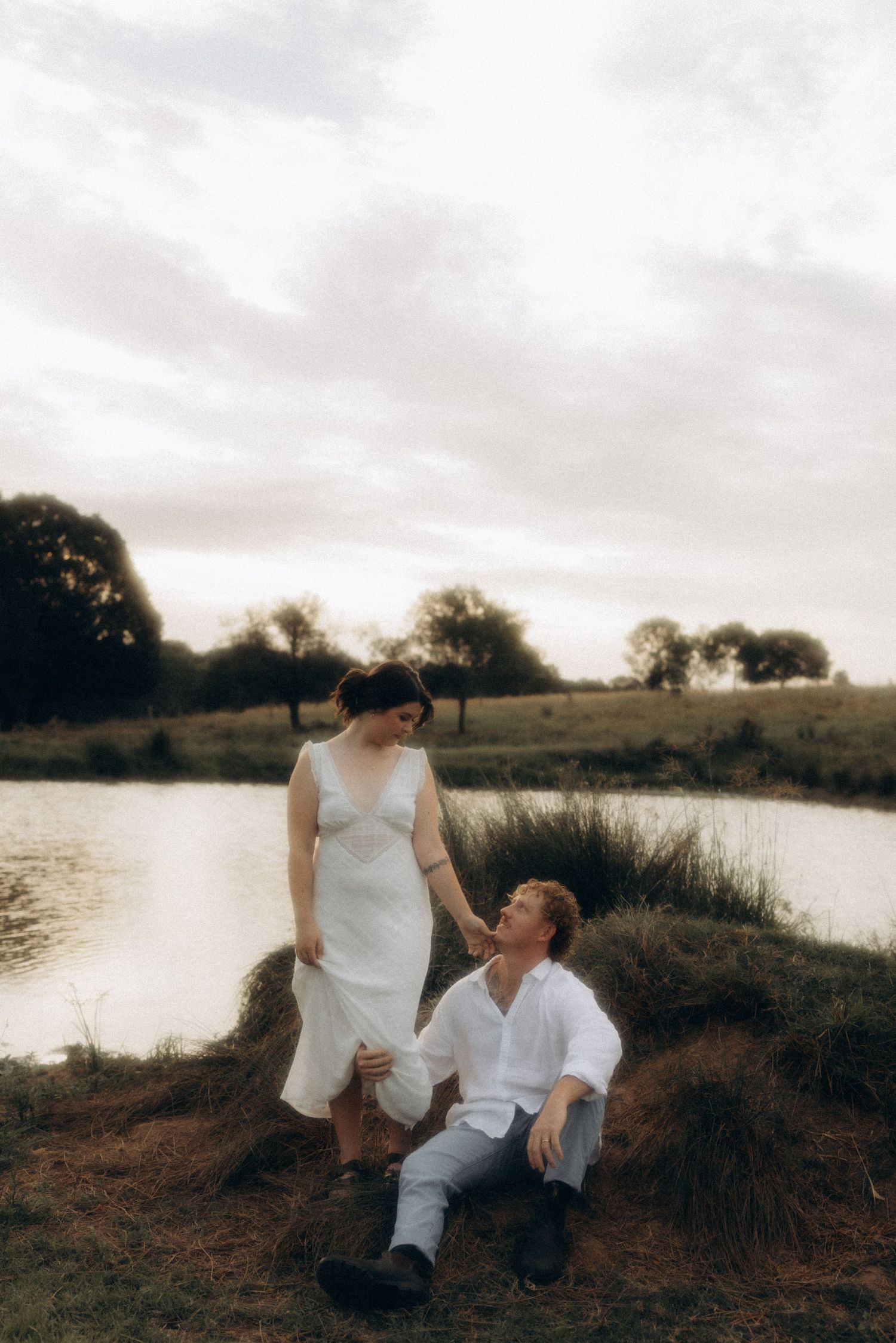 Couple sharing a playful moment by the lake at sunset.