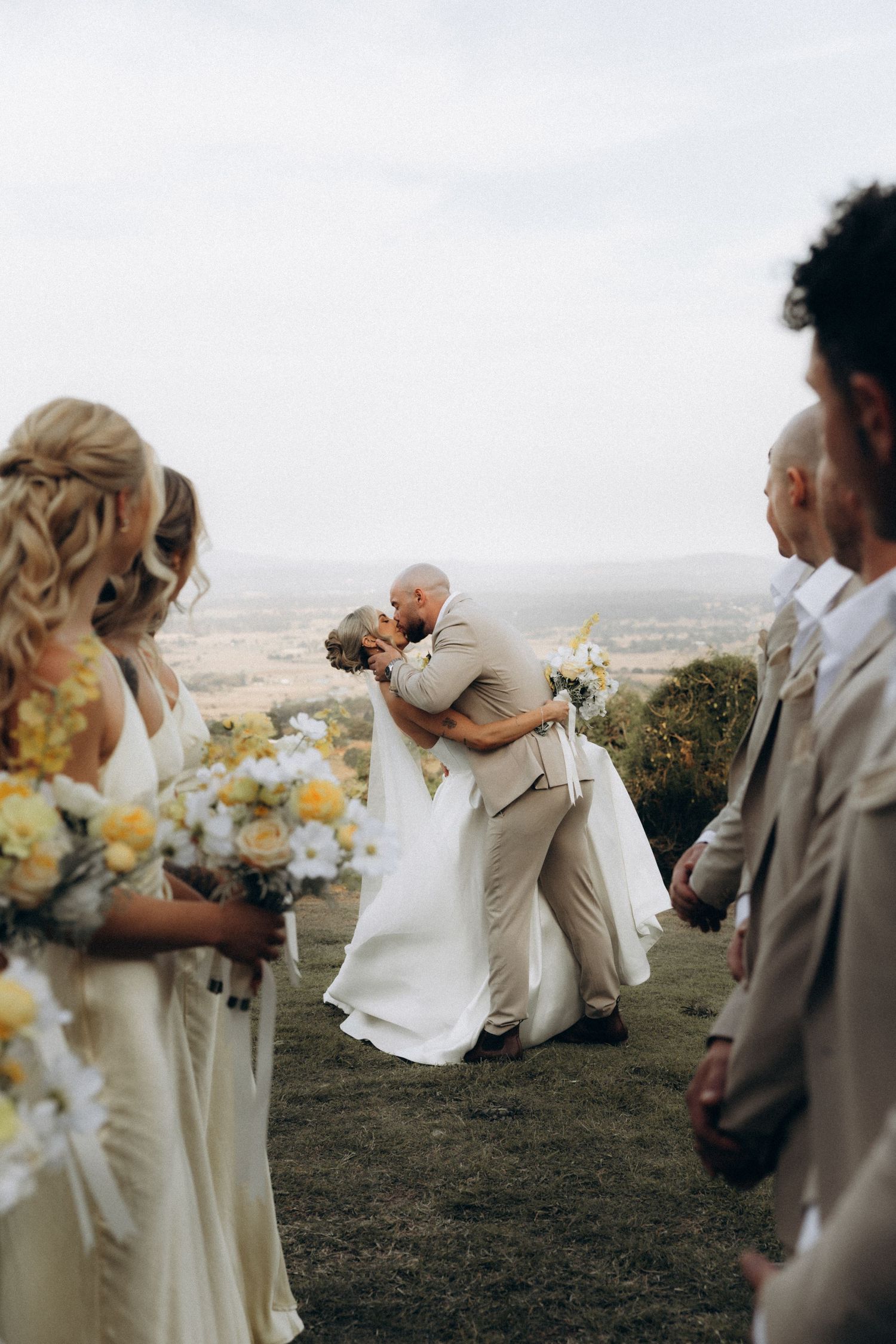 Newlyweds share a romantic dip kiss during their hilltop wedding ceremony.