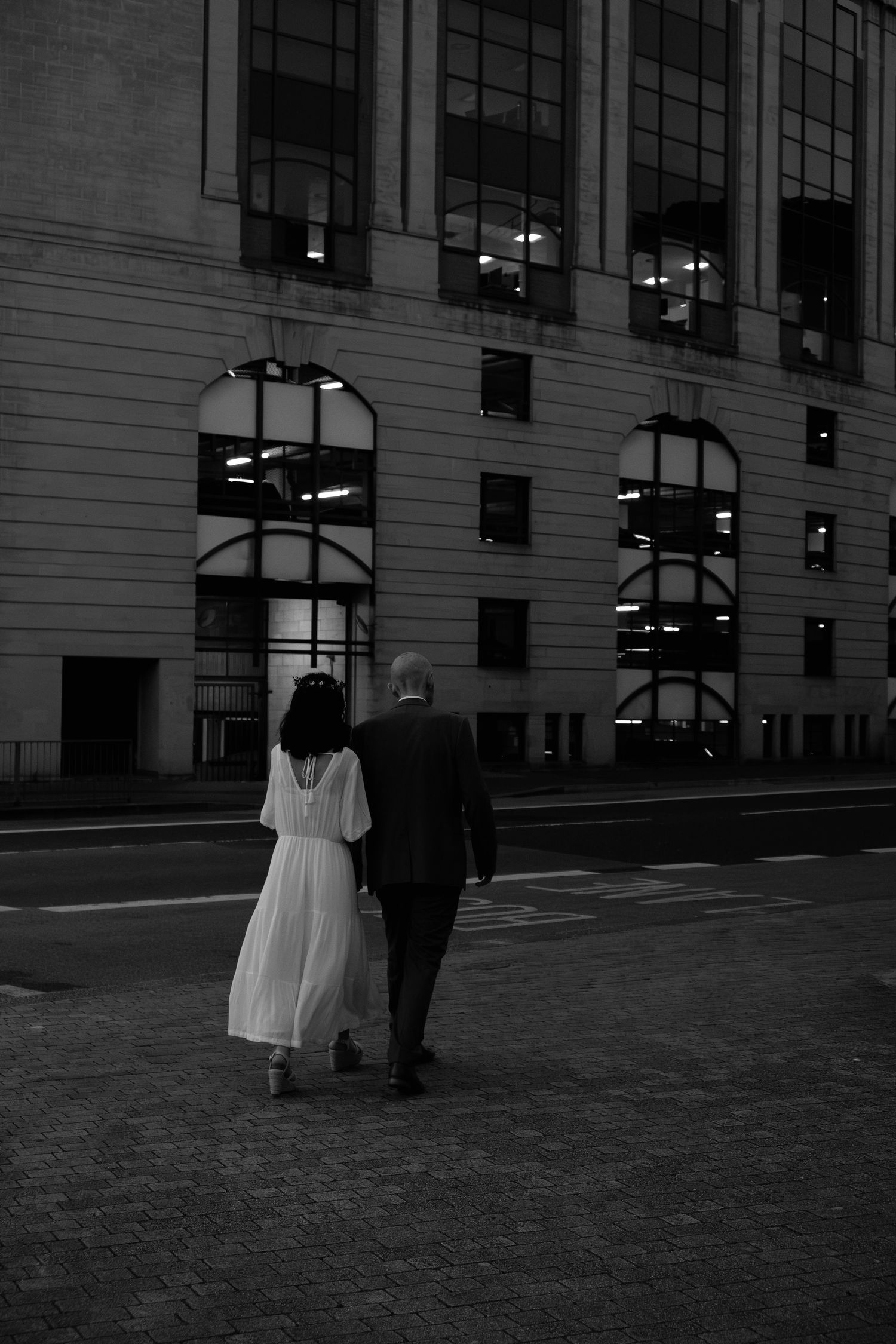 Bride and Groom walking together after their wedding day. Black and white image with tall building in the background.