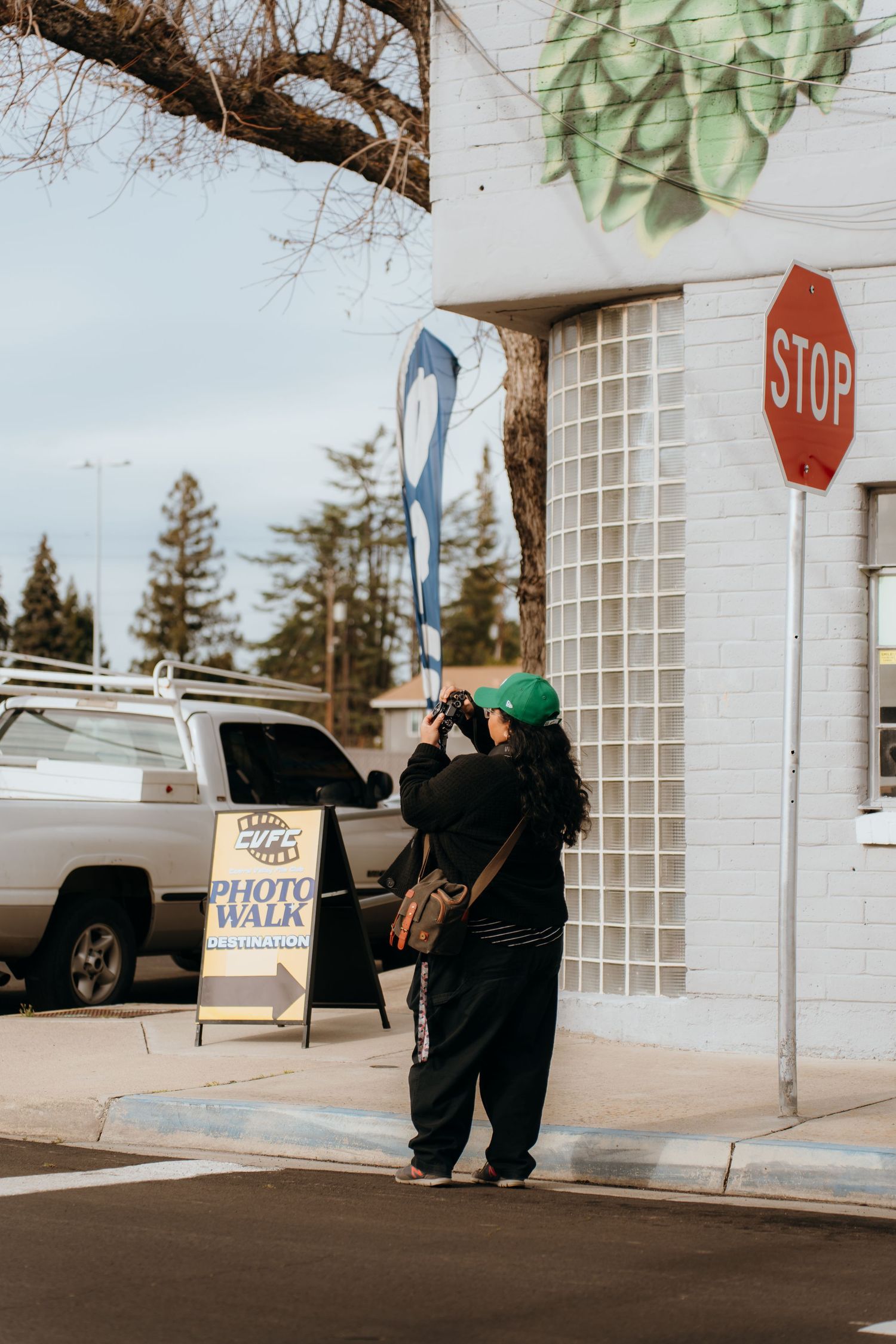 Person in dark clothing standing near a stop sign and white building.